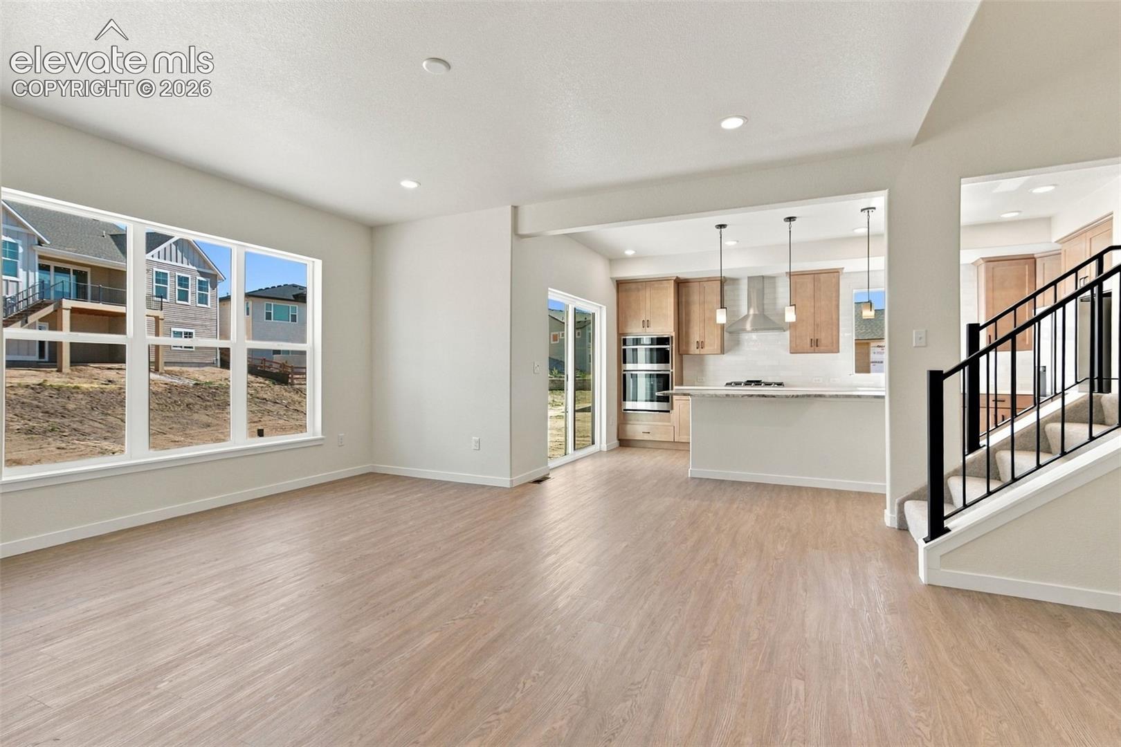 The Great Room features a Gas fireplace with stone extended to the ceiling, wood mantle, LVP Flooring, and recessed lighting.