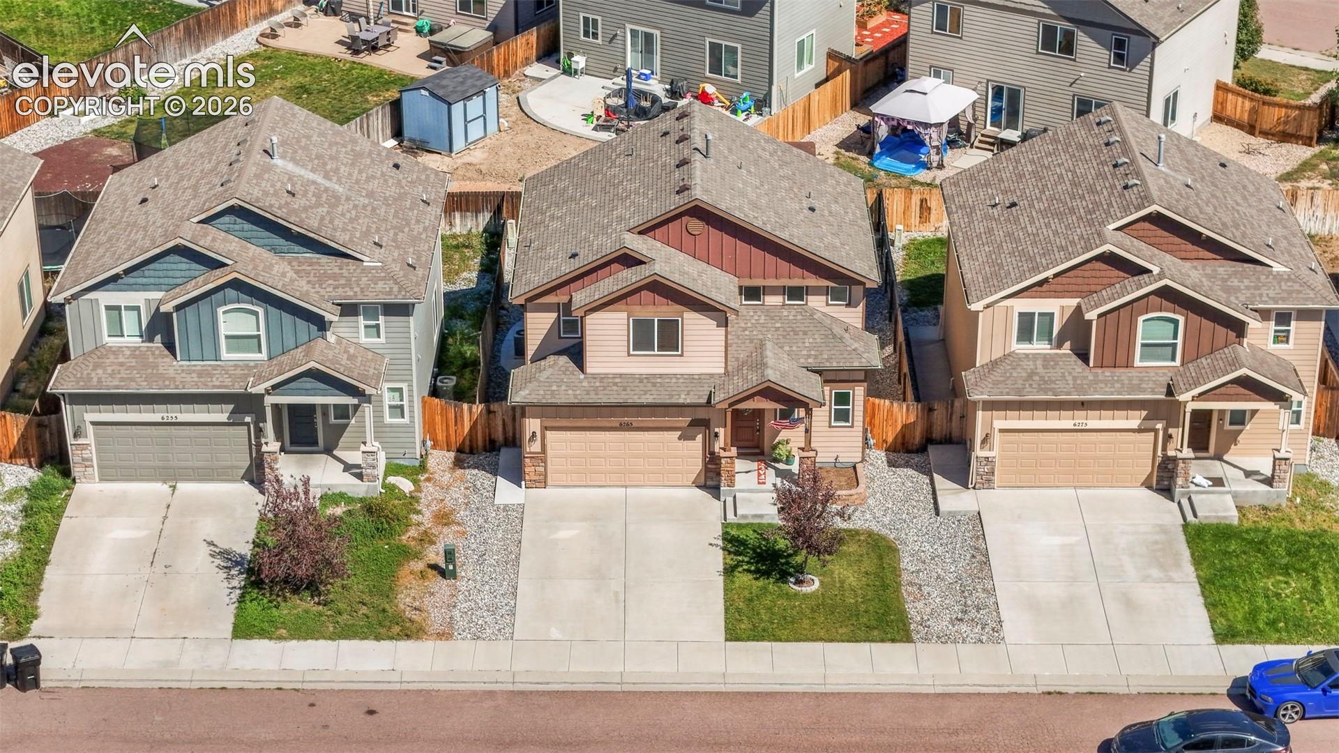 Two-story residential architecture with varied facade materials, attached garages, and a paved driveway