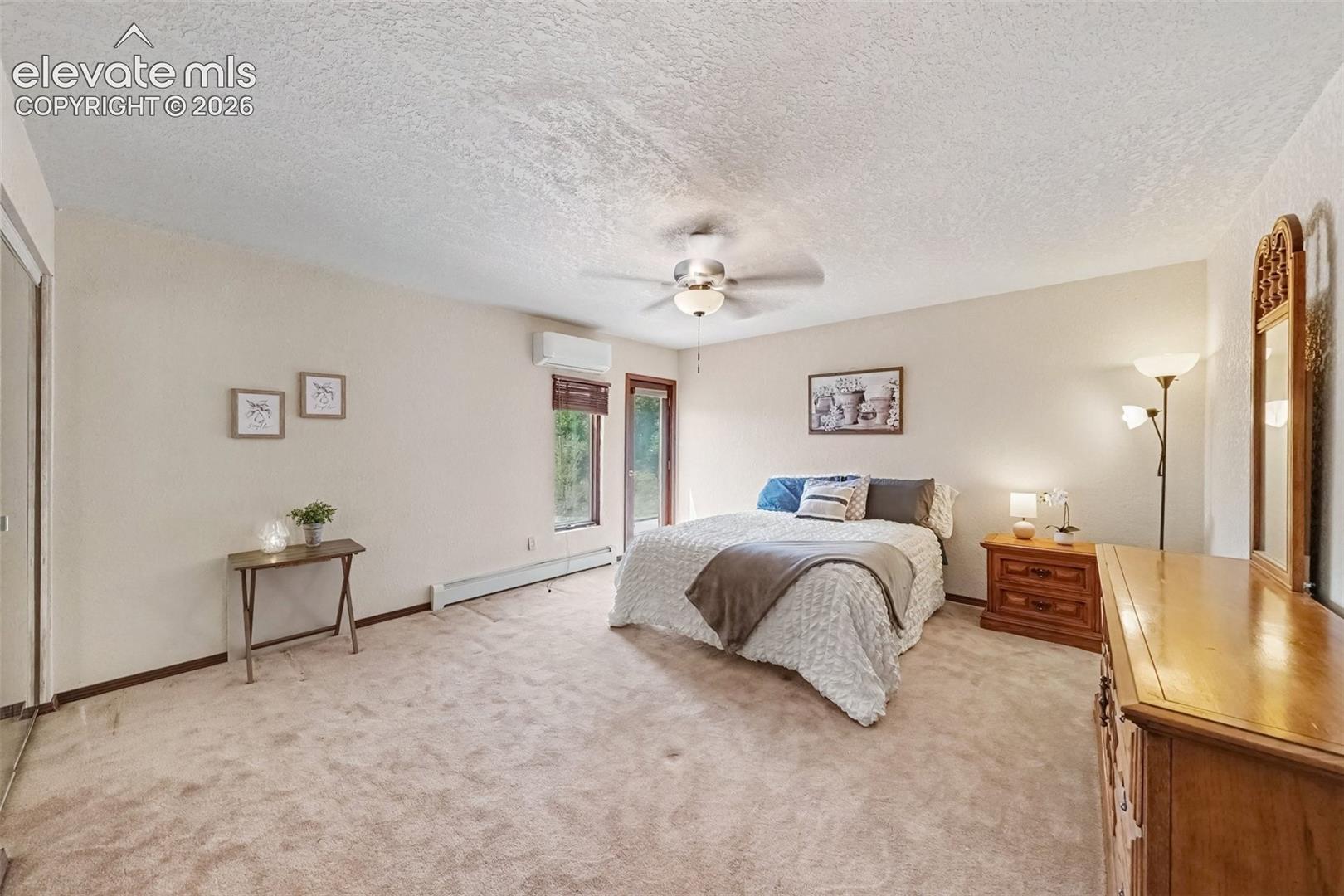 Spacious first main-level primary bedroom offers a peaceful retreat with a convenient walkout to the outdoors, bringing in natural light and connecting the room to the surrounding private setting