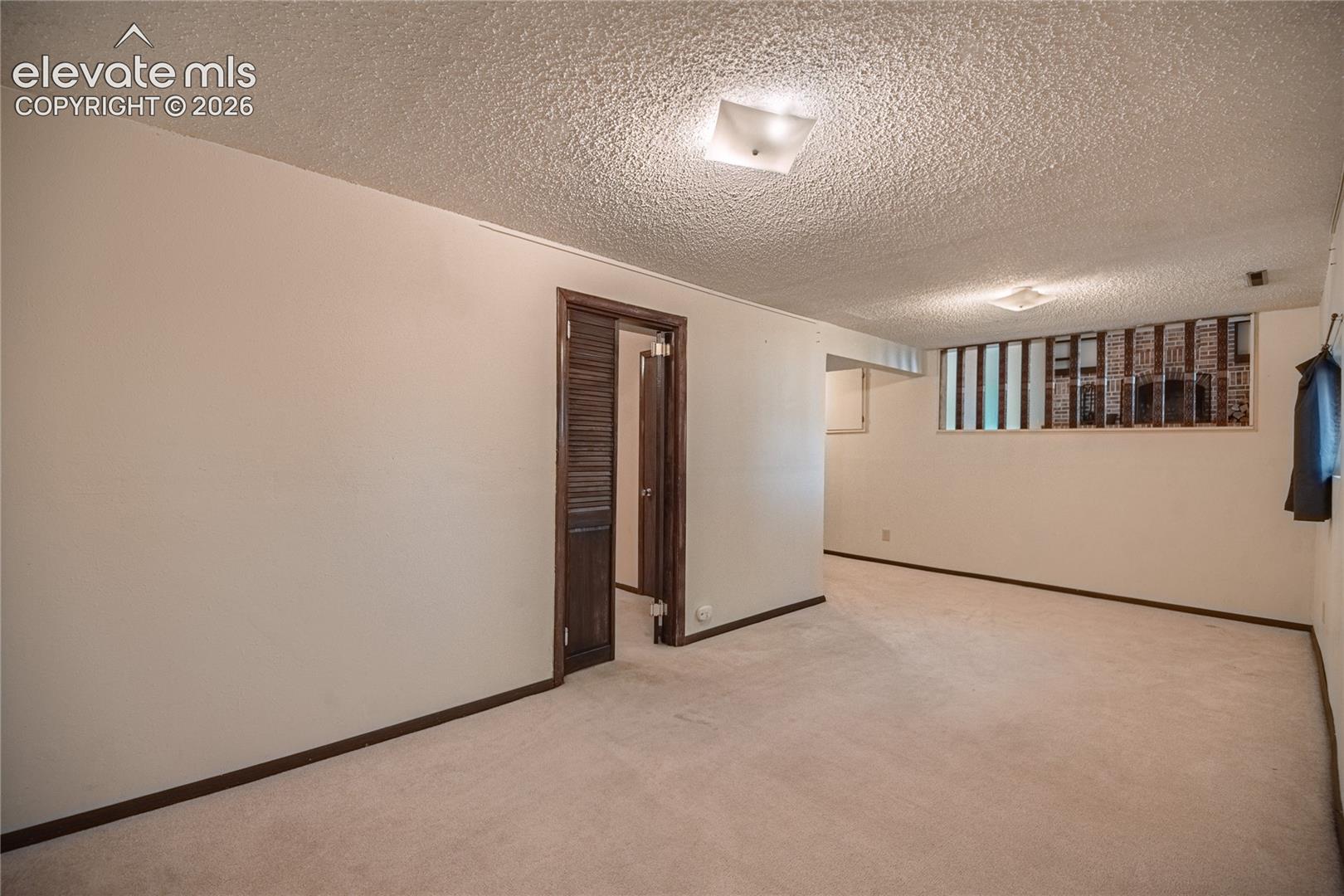 Interior room featuring textured ceiling, carpeted flooring, two square flush-mount ceiling lights, and a window with vertical panes