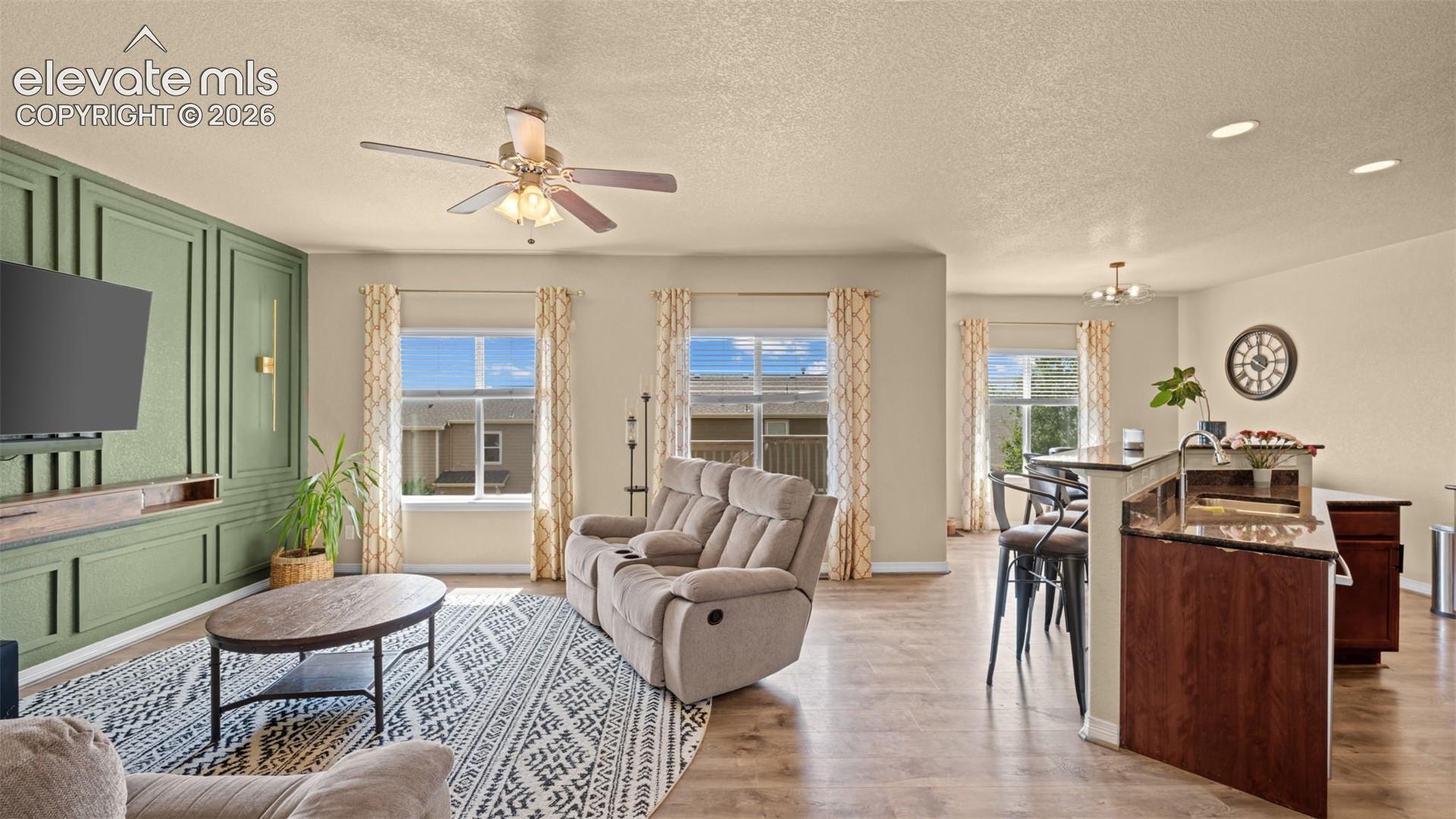 Open-concept living area featuring a built-in media console with decorative paneling and sconce lighting