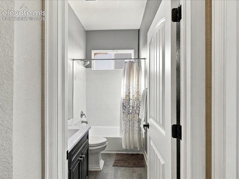 Bathroom featuring a white bathtub, wall-mounted showerhead, and a dark wood-finish vanity with a white countertop