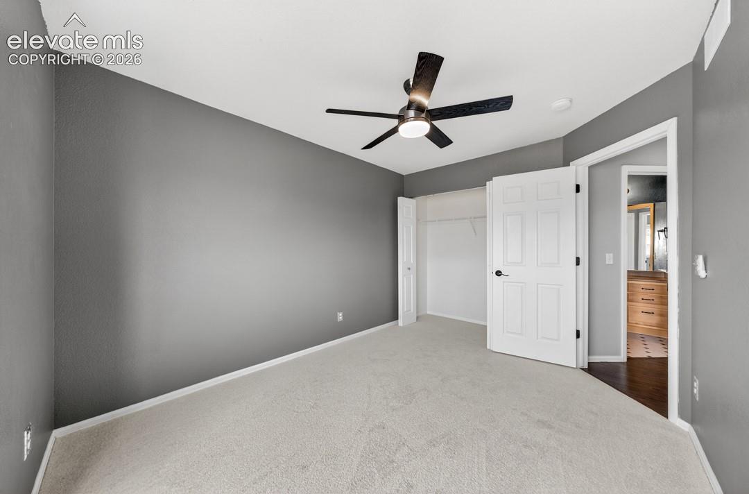 Room featuring neutral carpet, dark-toned wall paint, a ceiling fan with integrated lighting, and a closet with white paneled doors