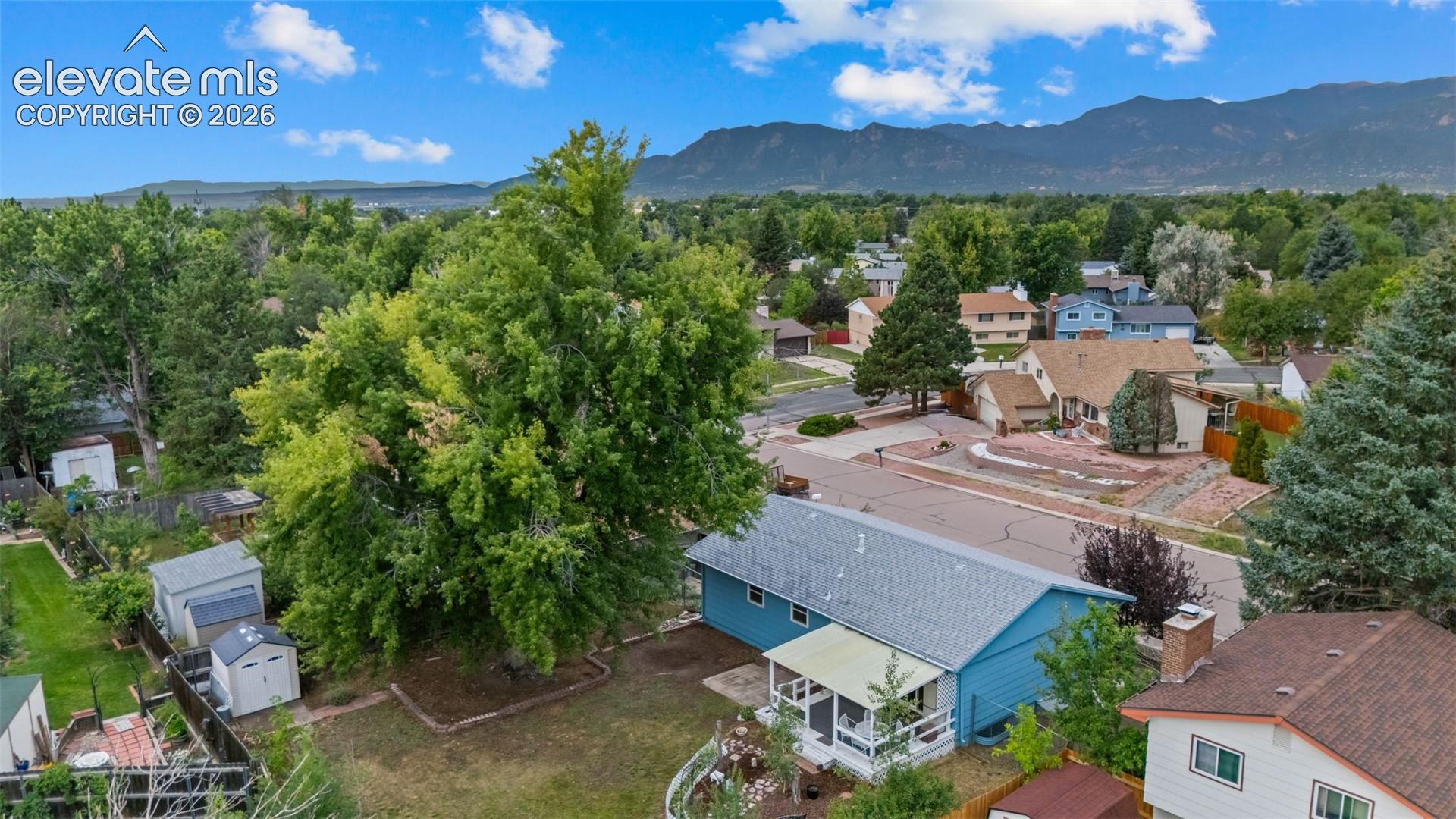 Aerial view showcasing this residential property nestled on a spacious lot with mature landscaping, including towering trees providing natural shade