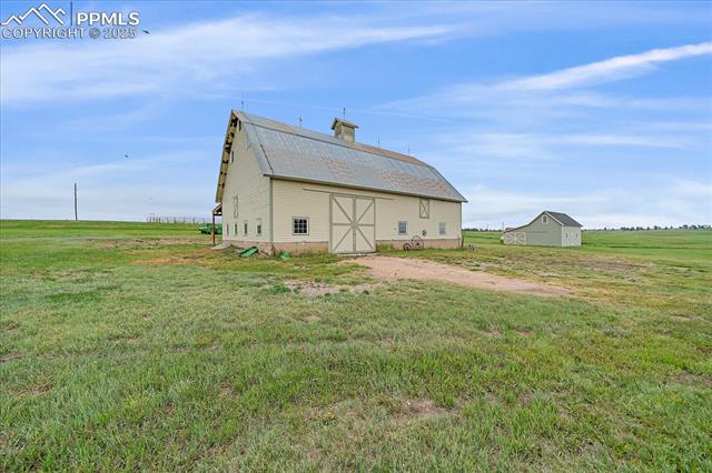 Back of property featuring a barn, an outbuilding, a lawn, and a chimney