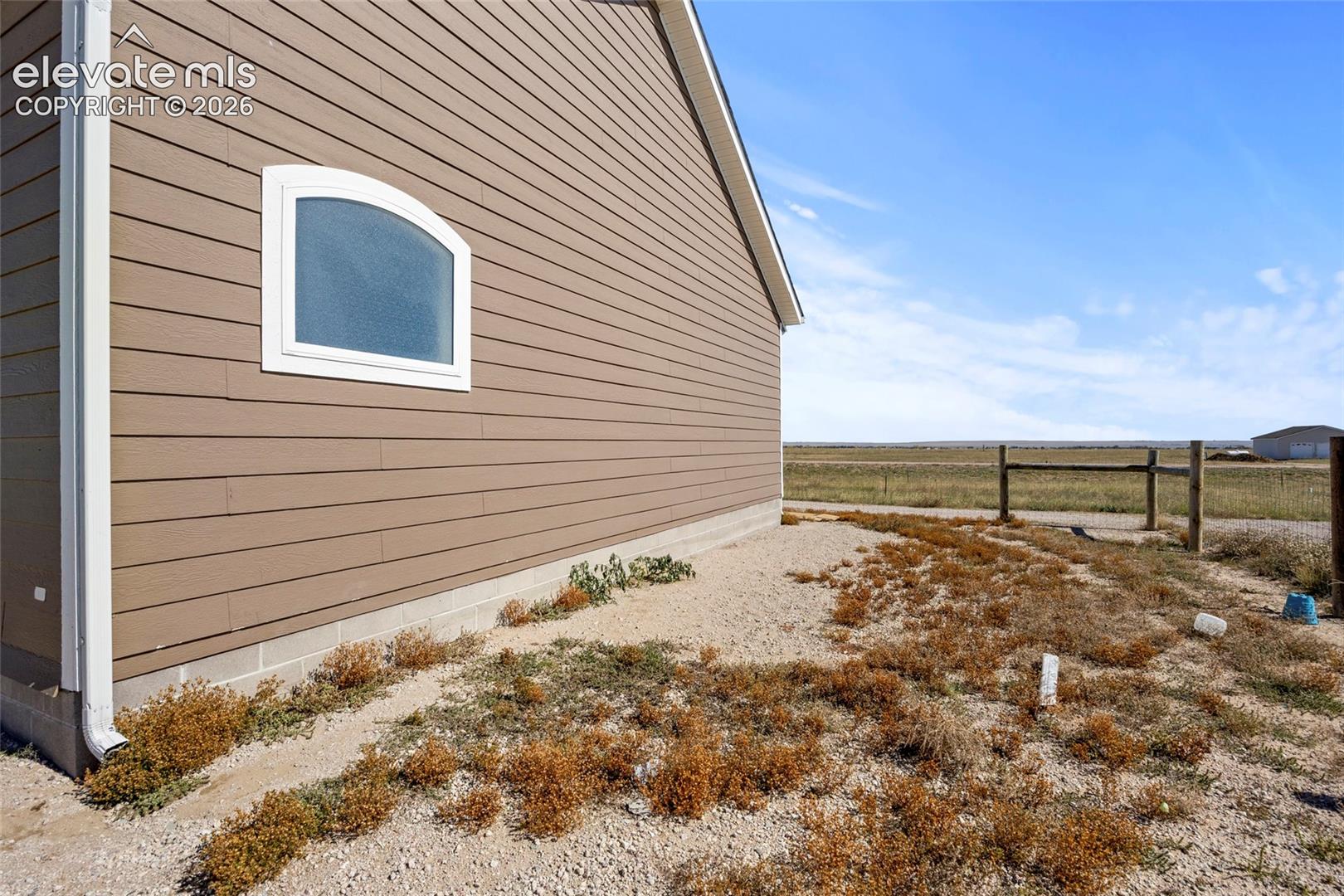 Horizontal siding exterior featuring a concrete foundation and a single arched window with white trim