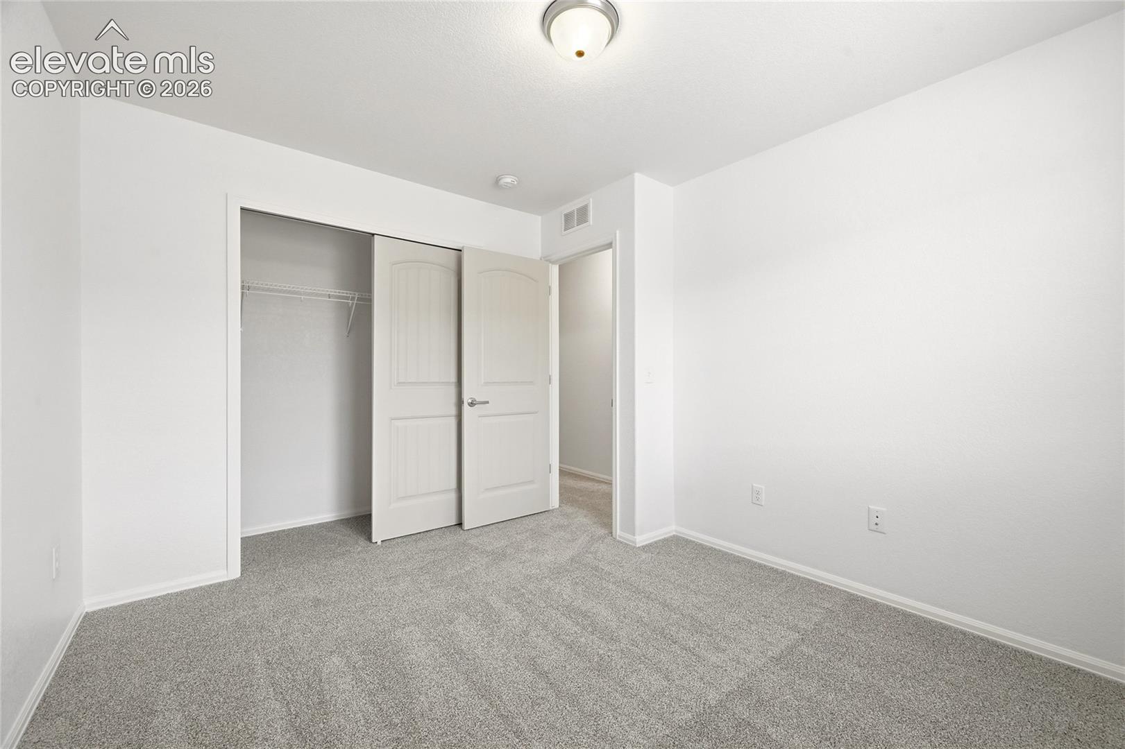 Neutral-toned carpeting, flush-mount dome lighting, and arched-panel interior closet doors