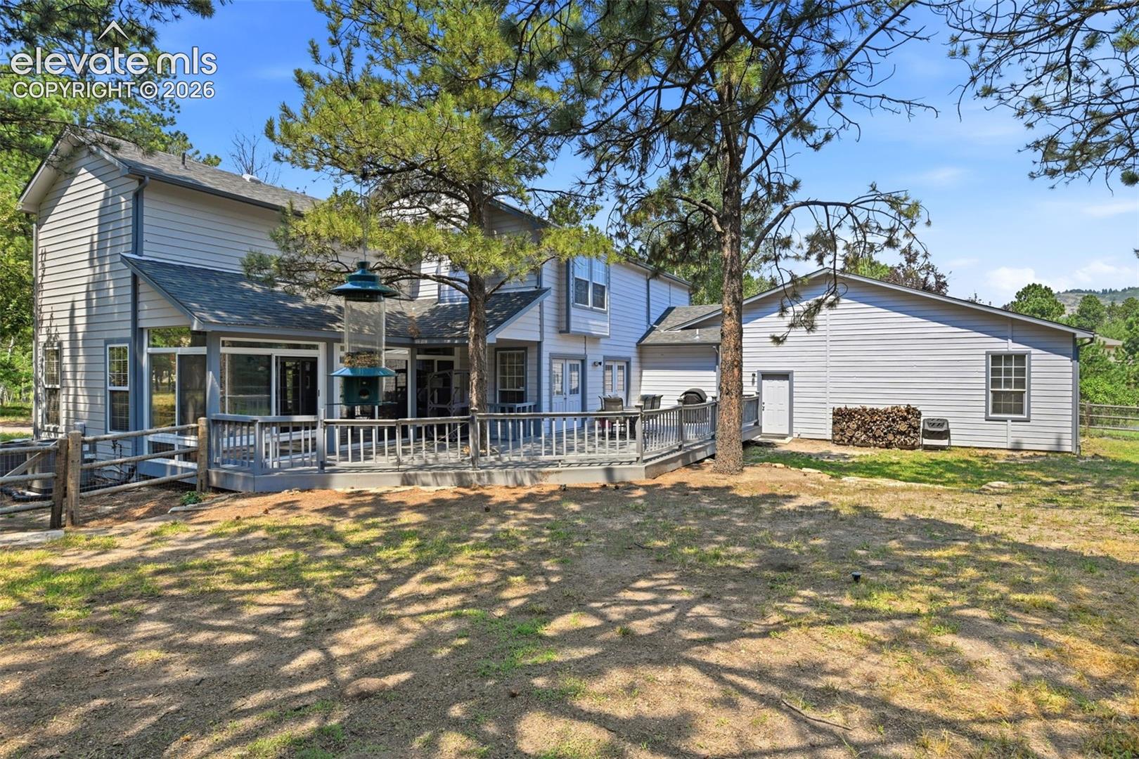 Expansive outdoor deck with railing, siding exterior, and mature trees