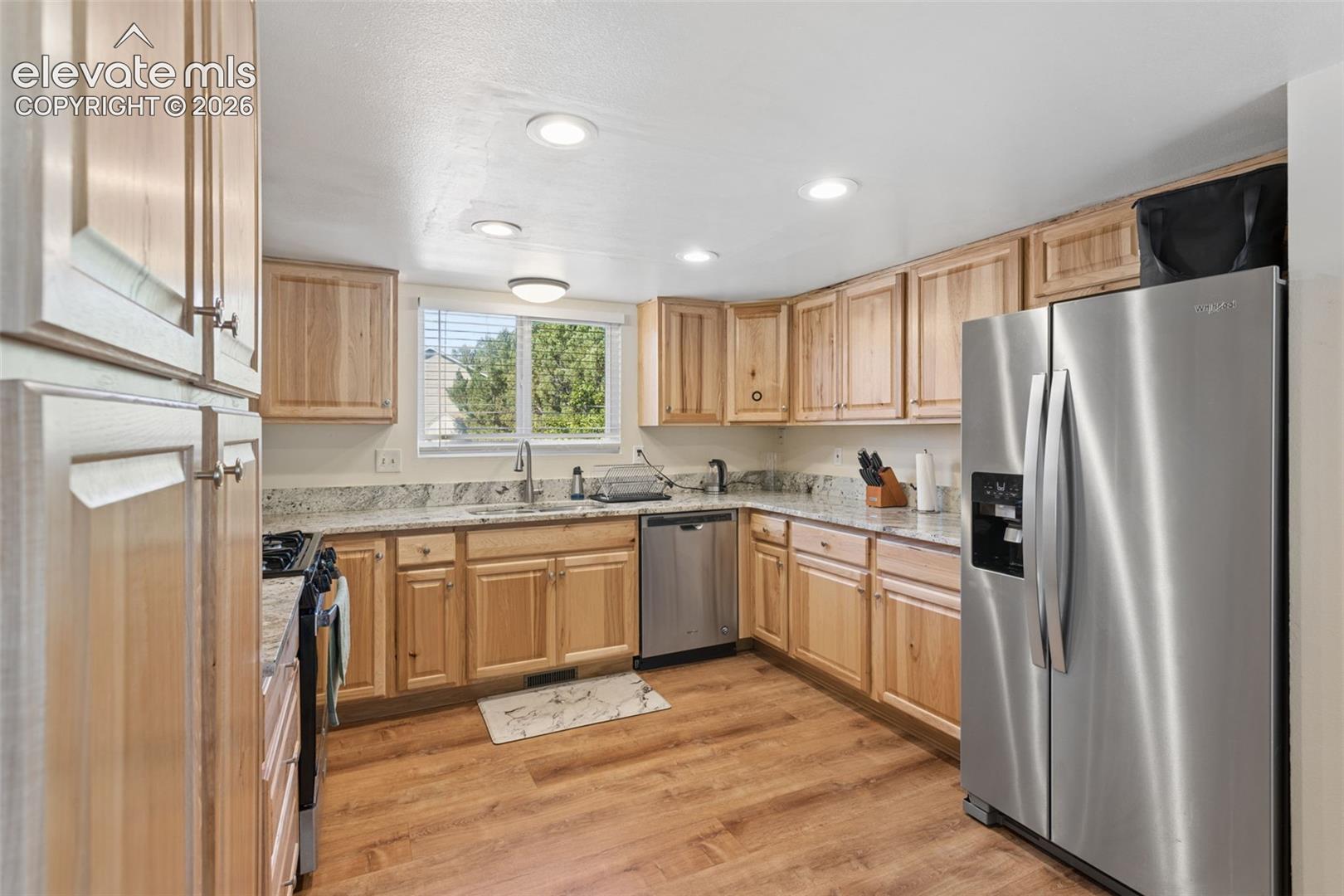 Kitchen featuring wood-finish flooring, light-toned cabinetry, light-colored countertops, stainless steel appliances, and recessed lighting