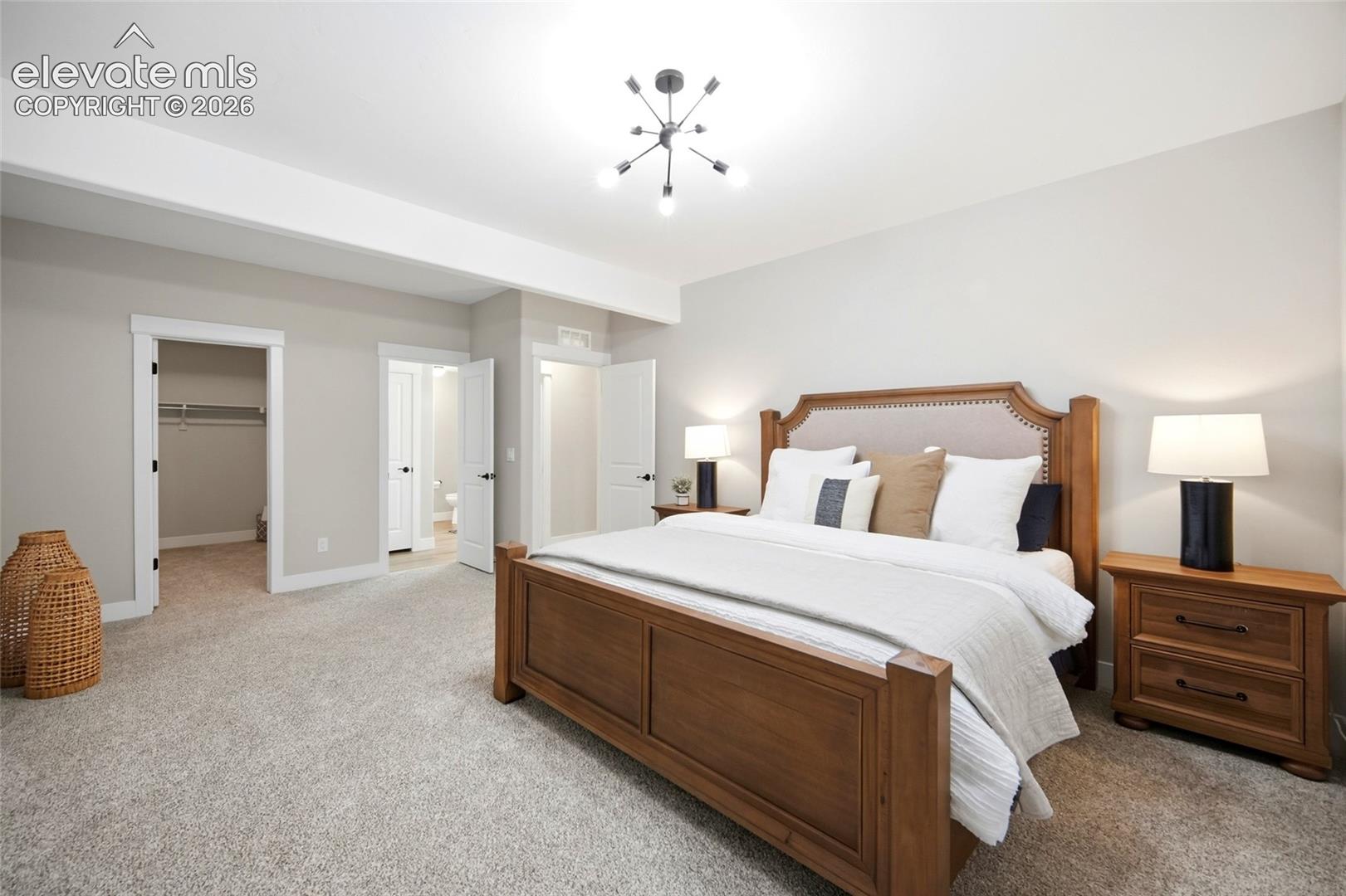 Spacious room featuring neutral carpeting, multi-light contemporary chandelier, and multiple doorways leading to interior storage and auxiliary spaces