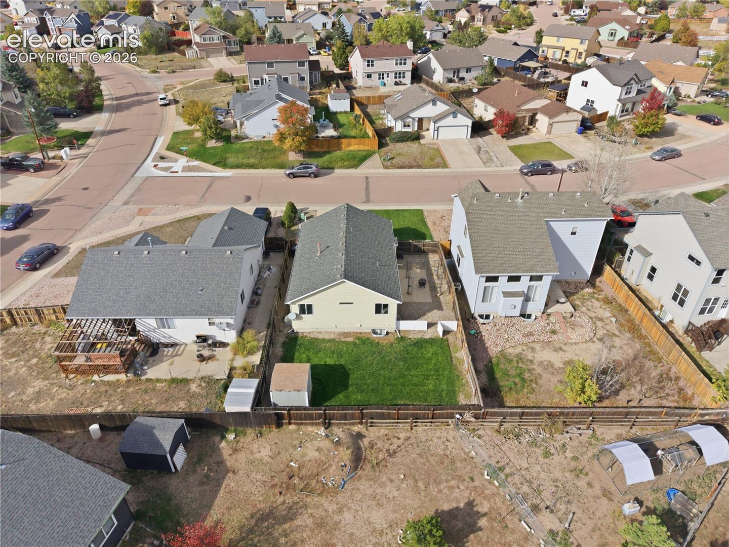 Expansive backyard featuring a manicured lawn, wood fencing, and a storage shed