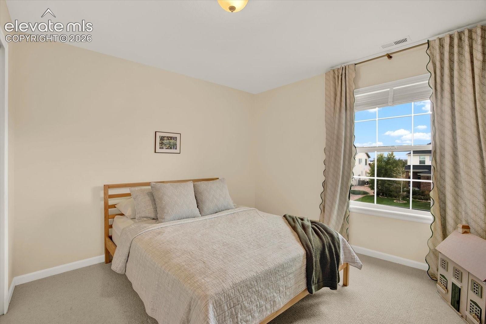 Neutral wall tones, wall-to-wall carpeting, and a double-hung window with a grid pattern