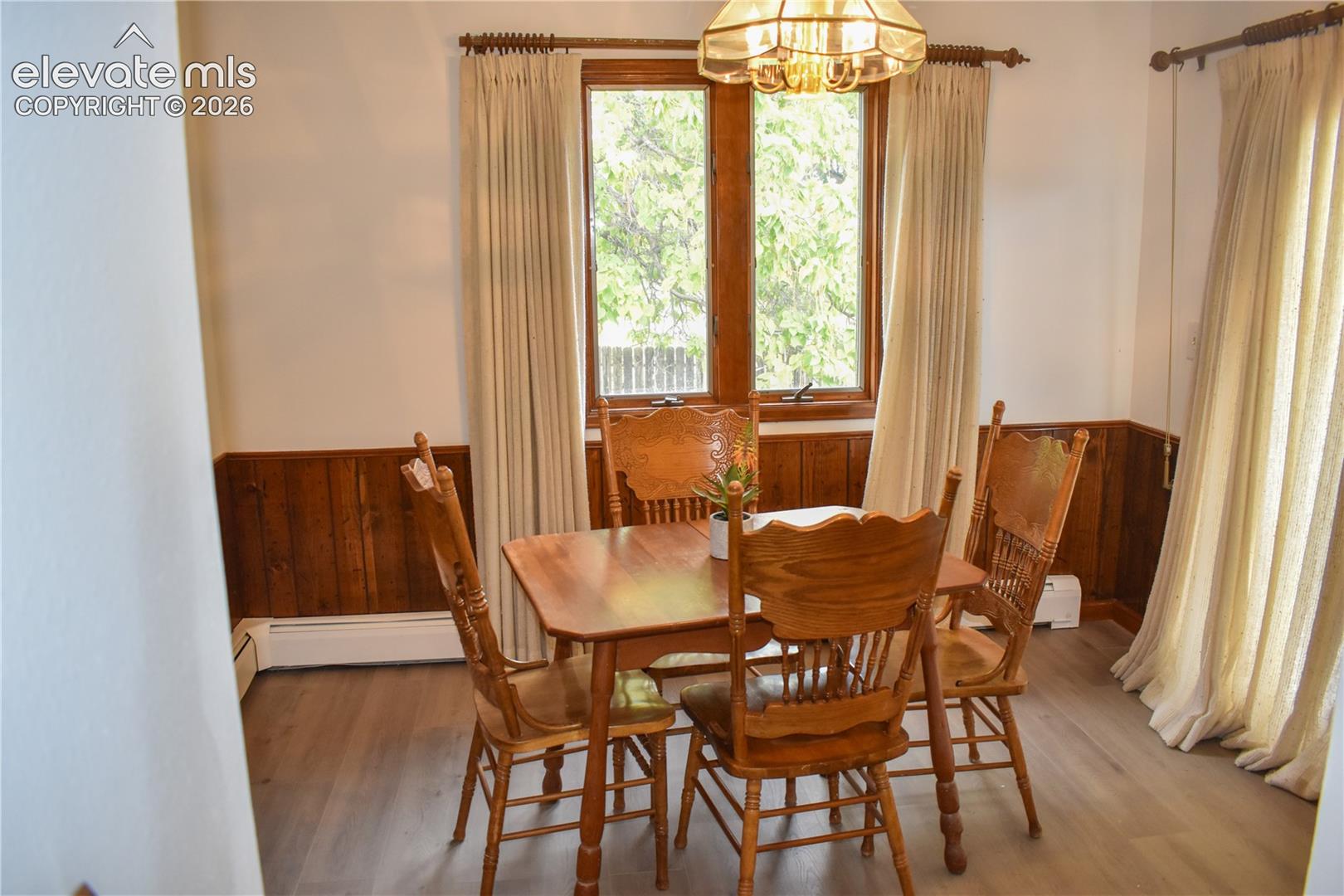 Wood-finish flooring with wainscoting and natural wood window trim