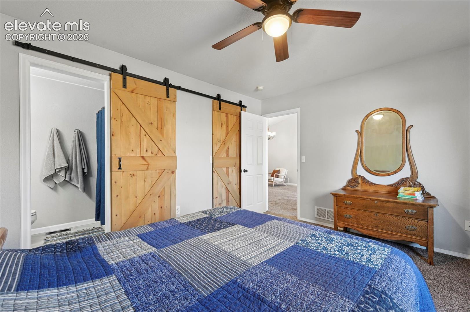 Primary Bedroom: Dual sliding wood barn doors, ceiling fan 