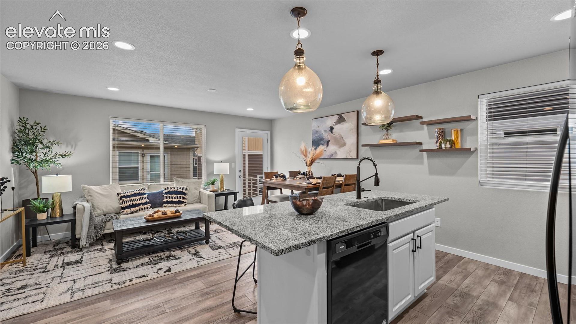 Kitchen featuring a stone-surface island, white cabinetry, matte black hardware, recessed lighting, and wood-finish flooring