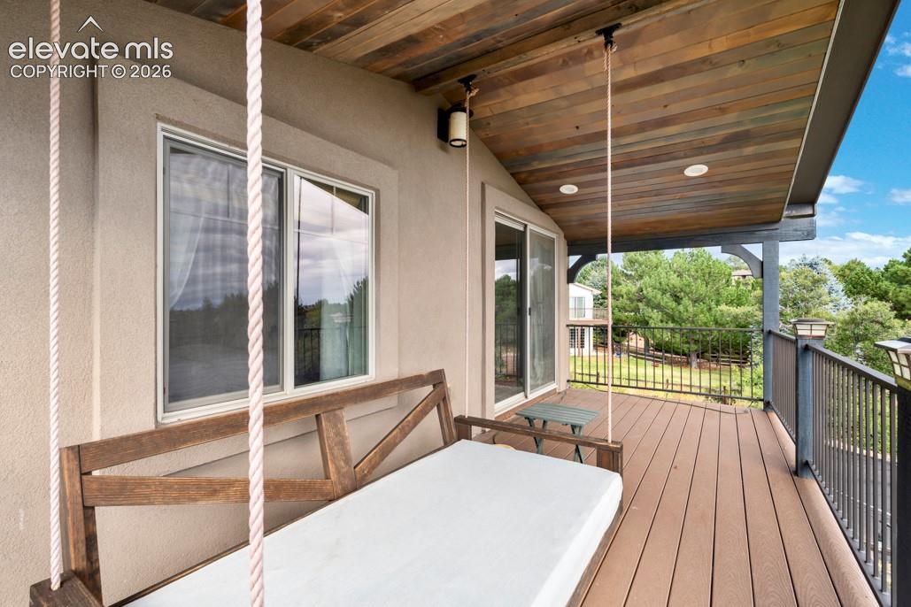 Spacious outdoor deck with composite decking, a wood-paneled ceiling, recessed lighting, and a dark metal railing