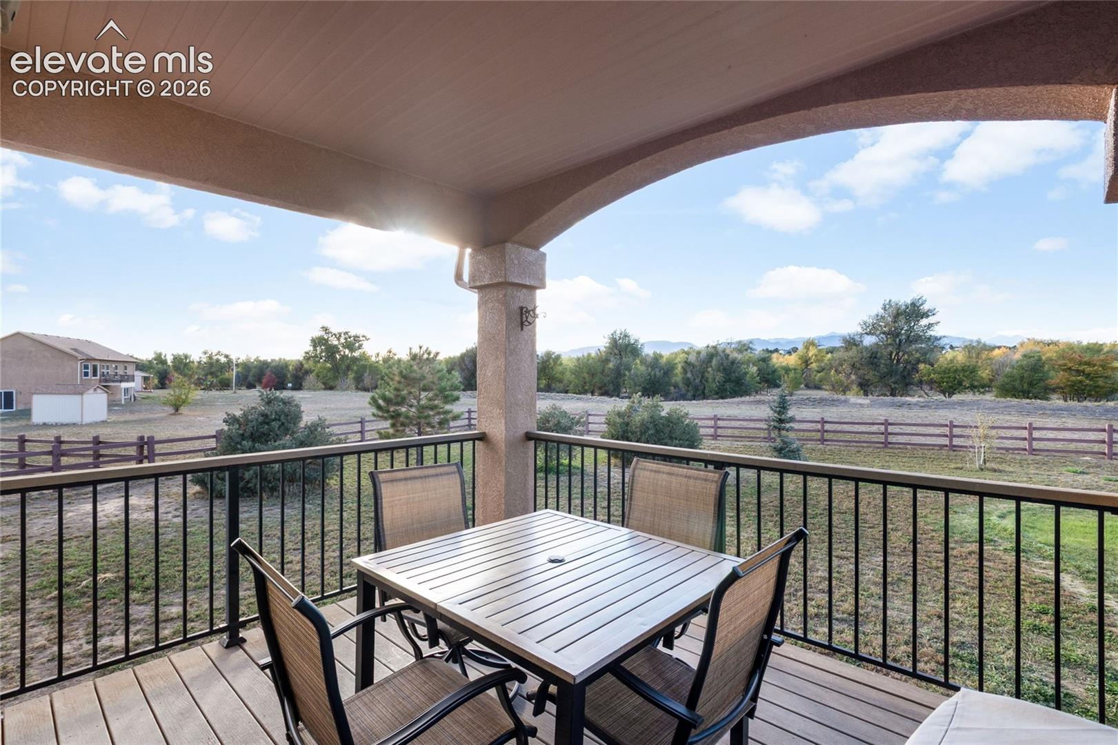 covered composite deck with views of Pikes Peak looking over large yard