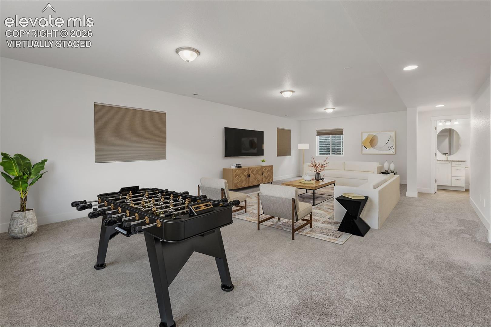 Virtually staged:  Spacious finished lower level featuring recessed lighting, light gray carpeting, and a powder room