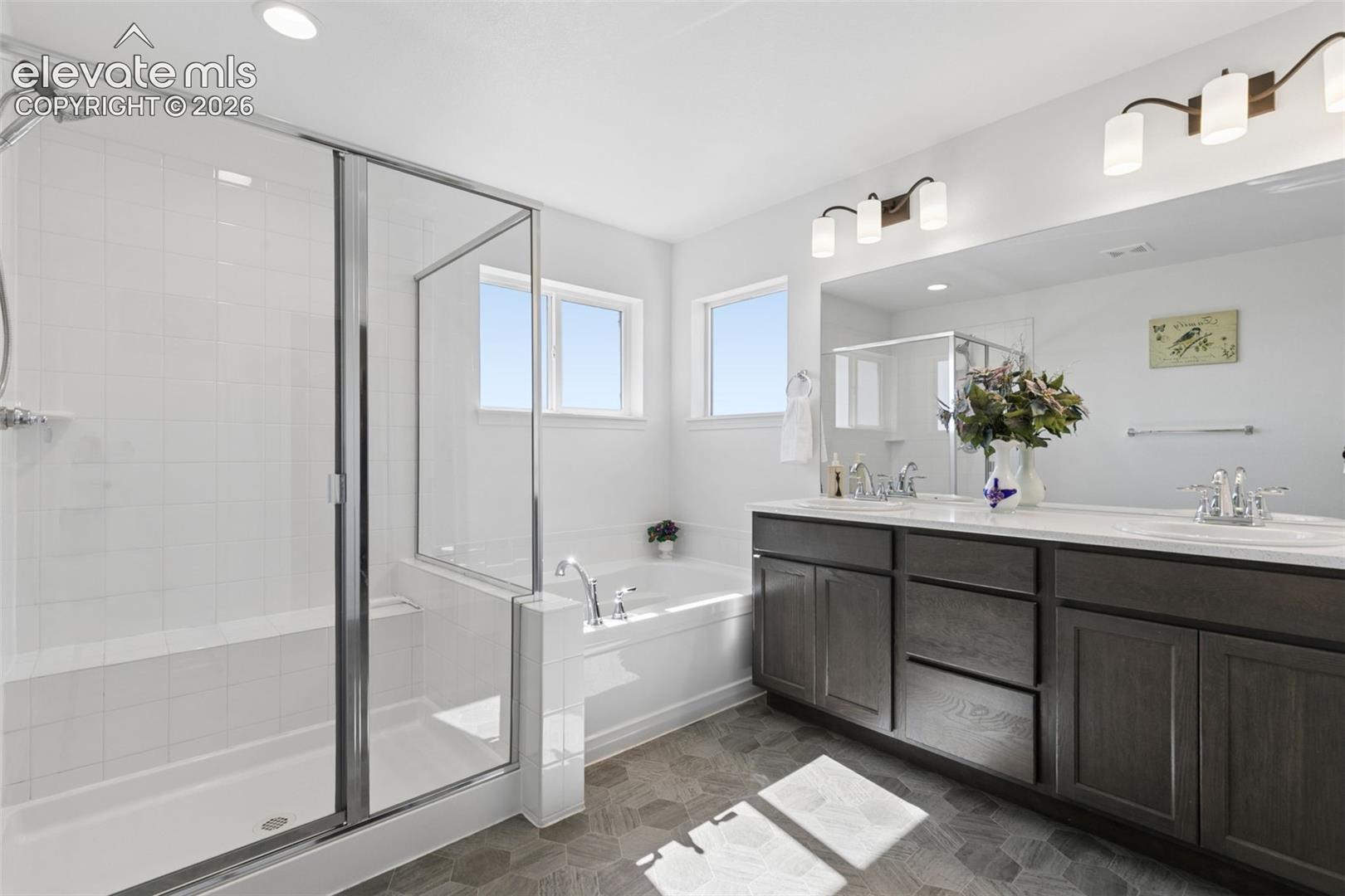 Spacious bathroom featuring a glass-enclosed shower, built-in soaking tub, dual vanity with undermount sinks.