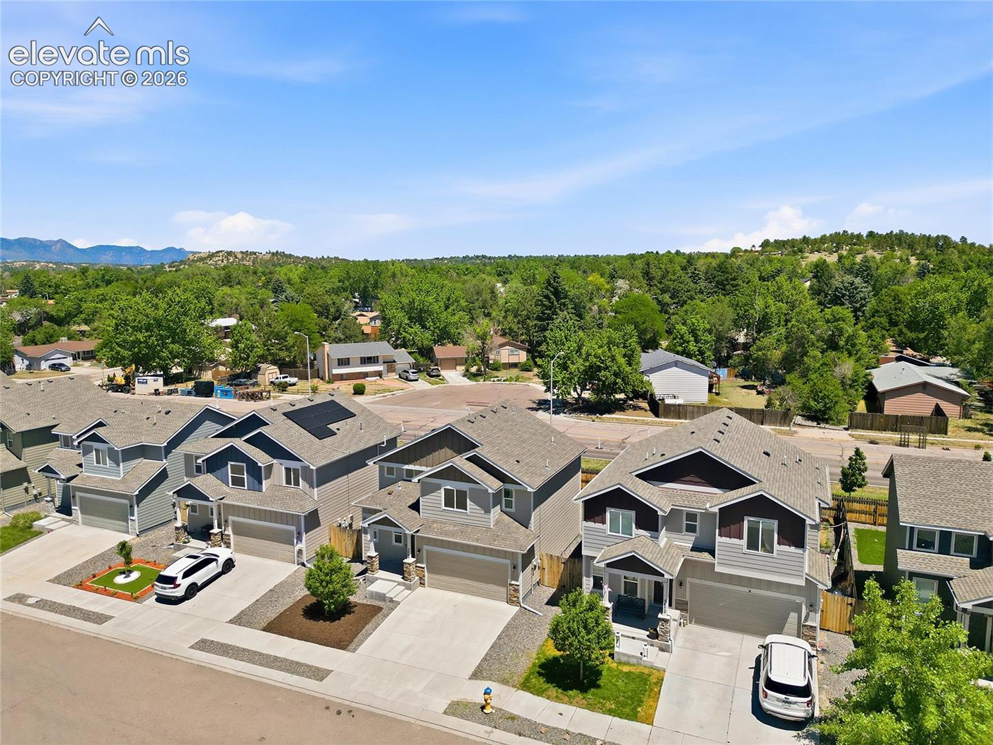 Modern residential streetscape featuring two-story homes with attached garages, concrete driveways, and manicured landscaping