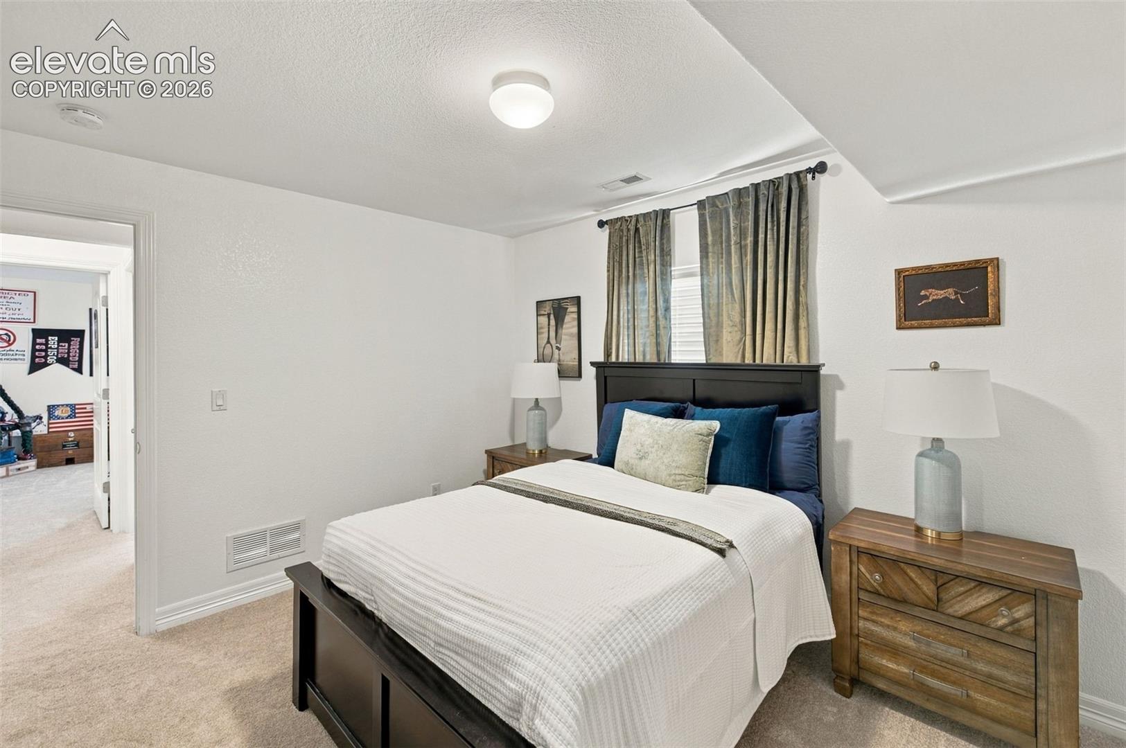 Neutral-toned carpeted flooring, textured walls, and a recessed window nook featuring decorative rod hardware
