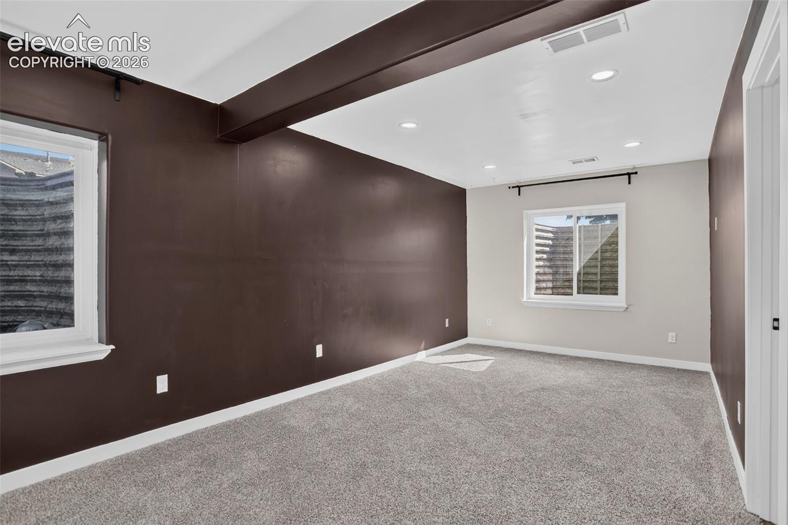 Recessed ceiling lighting, gray carpeting, dual windows, contrasting wall finishes, and a white trim package