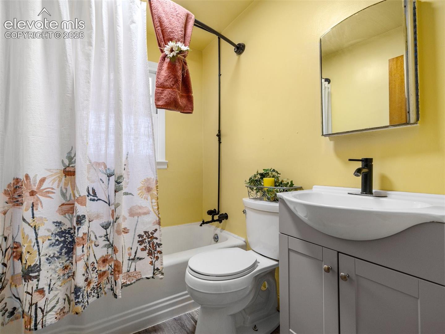 Bathroom featuring a grey vanity with a vessel sink, black faucet hardware, a wall-mounted medicine cabinet, and a bathtub with black exposed plumbing fixtures