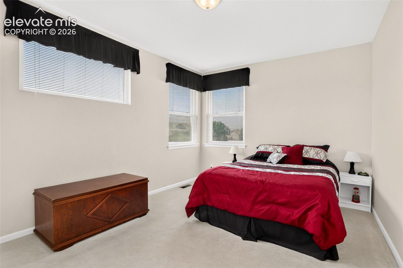 White walls, carpet flooring, and multiple windows with blinds