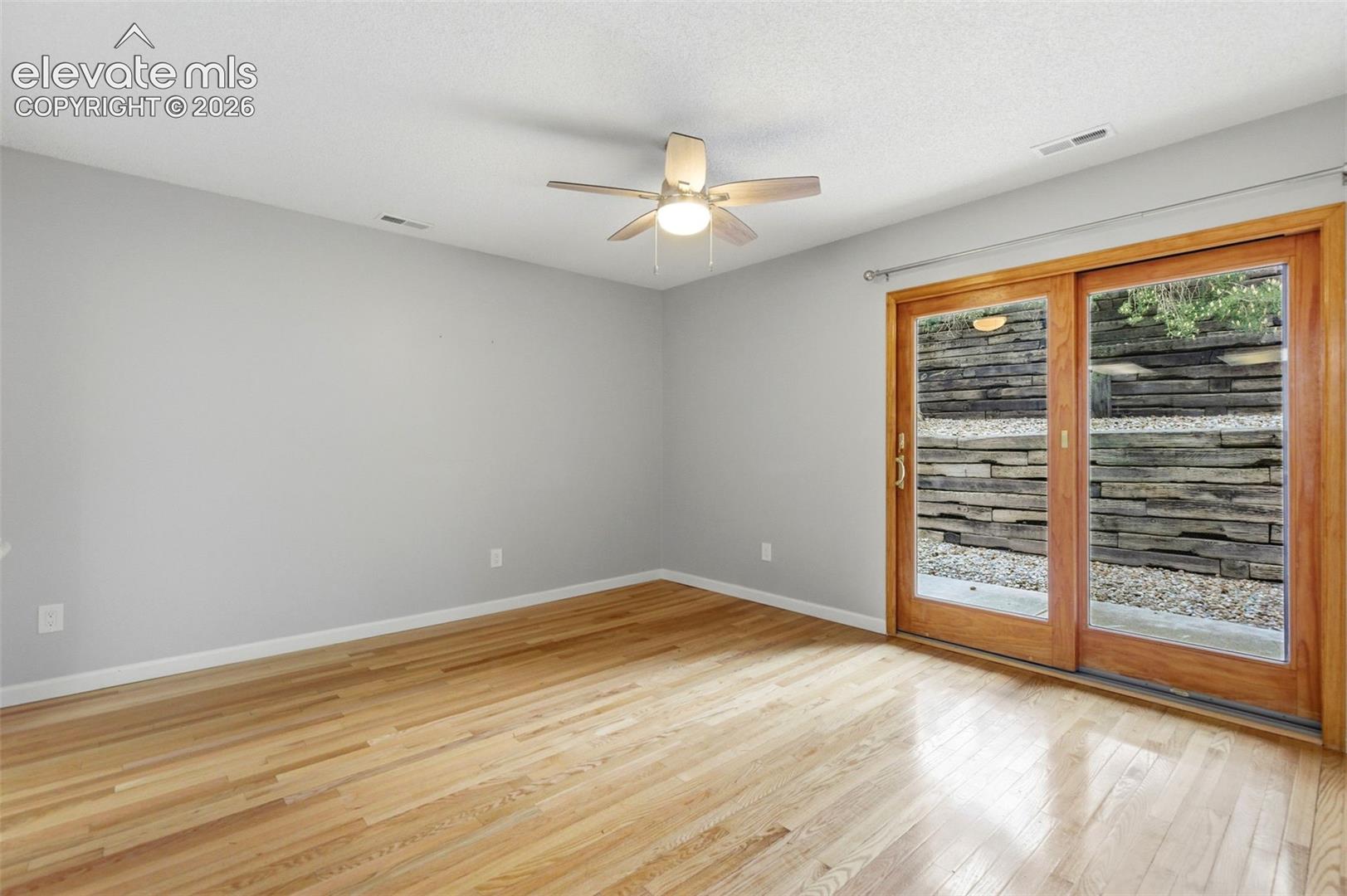 Bright room featuring wood-finish flooring, a ceiling fan with integrated lighting, and neutral wall paint