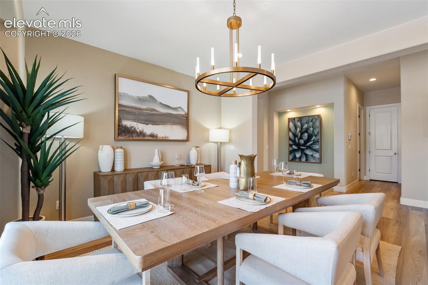 Dining area featuring wood-finish flooring, a contemporary circular metal chandelier, a recessed wall niche with integrated lighting, and neutral wall tones