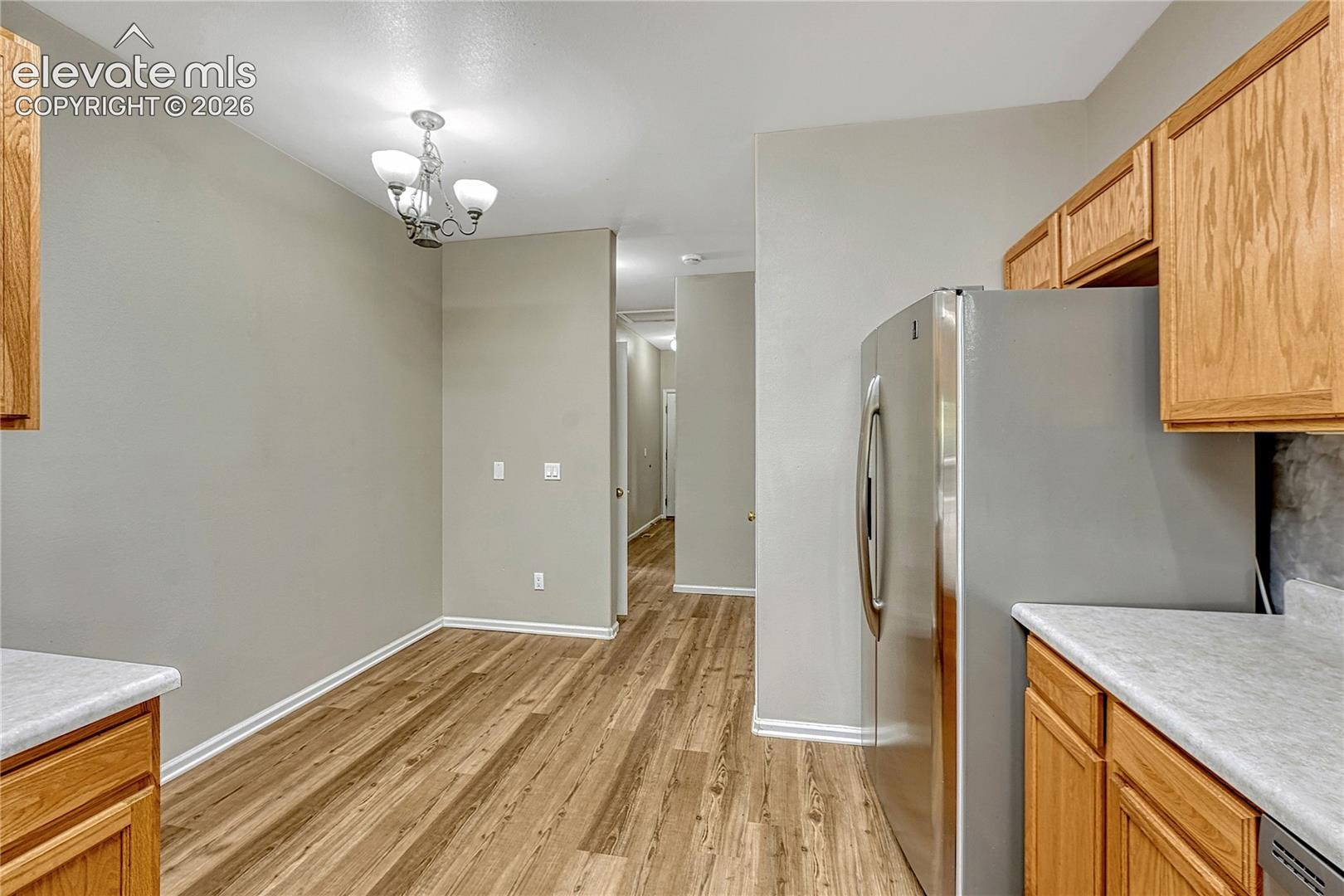 Kitchen featuring wood-finish flooring, natural wood cabinetry, light-toned countertops, and a multi-light chandelier
