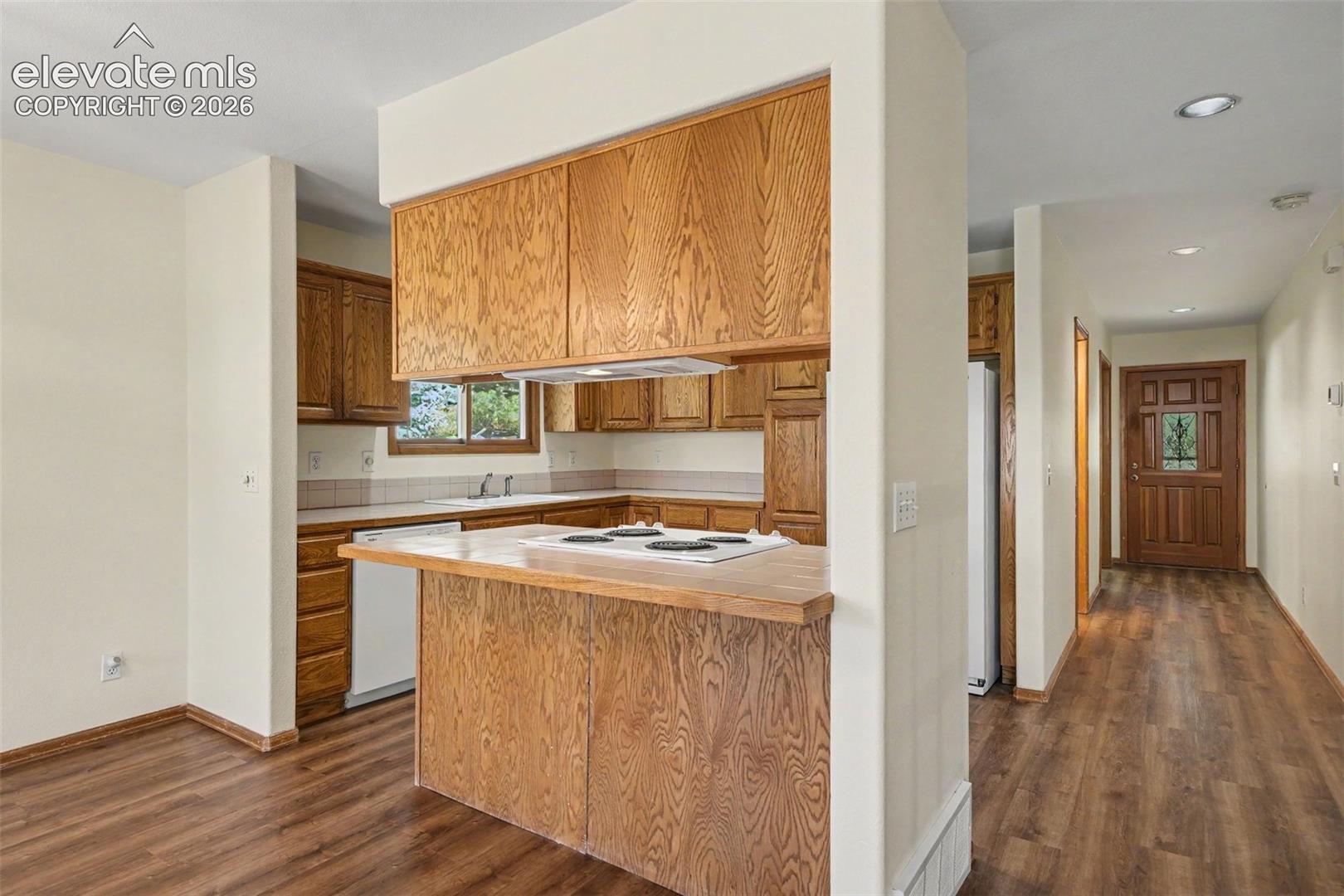 Kitchen featuring wood cabinetry, white appliances, and a breakfast bar