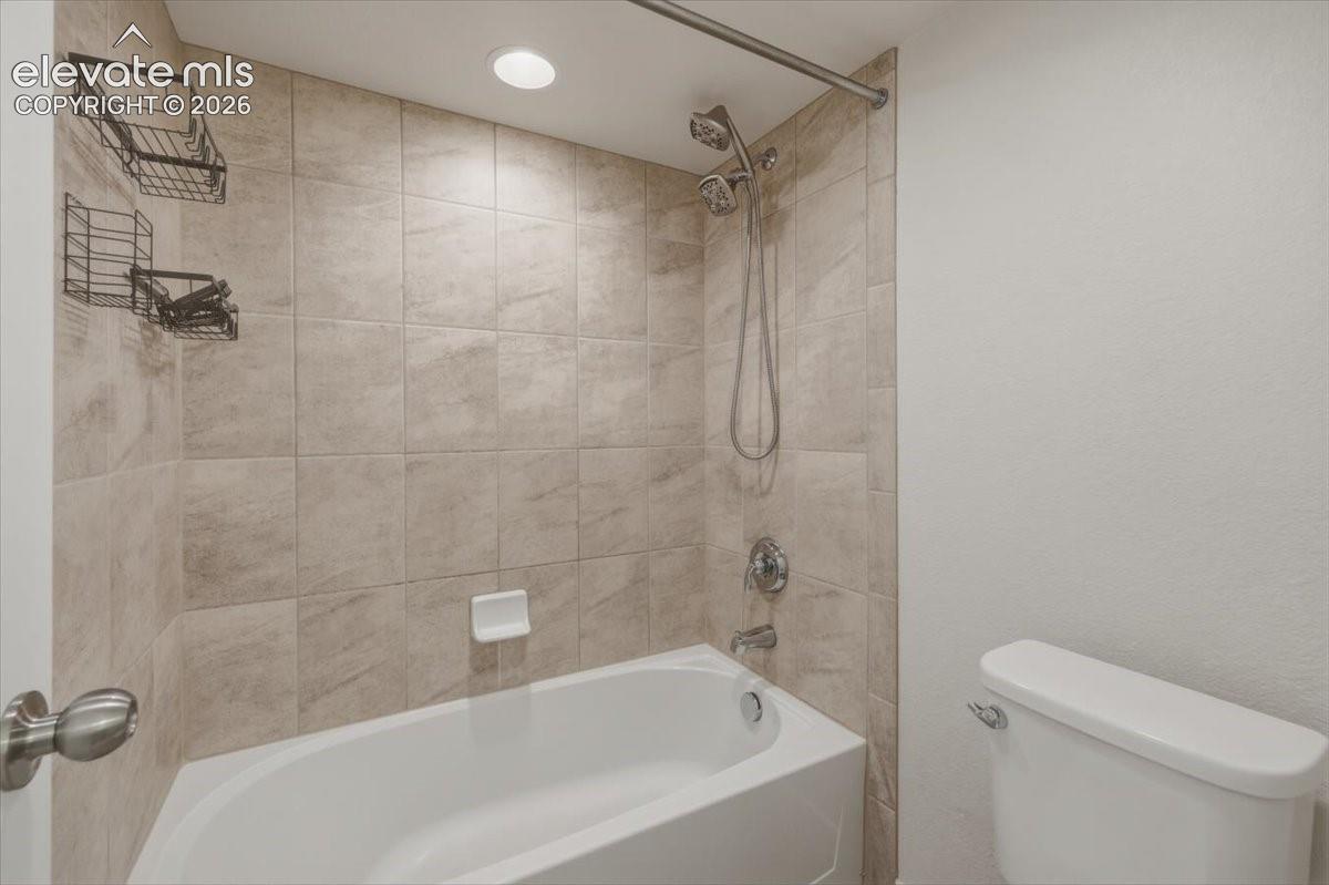 Full bathroom featuring a white tub, chrome fixtures, and neutral-toned wall tiling