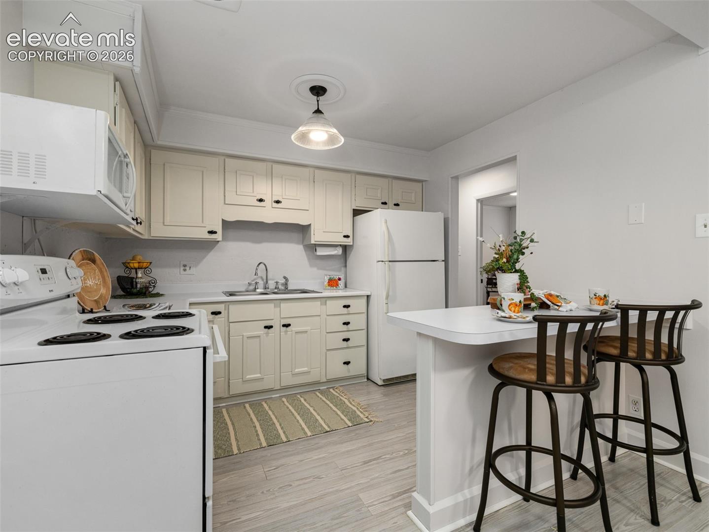 Kitchen featuring light-toned cabinetry, a built-in microwave, and a breakfast bar/ island