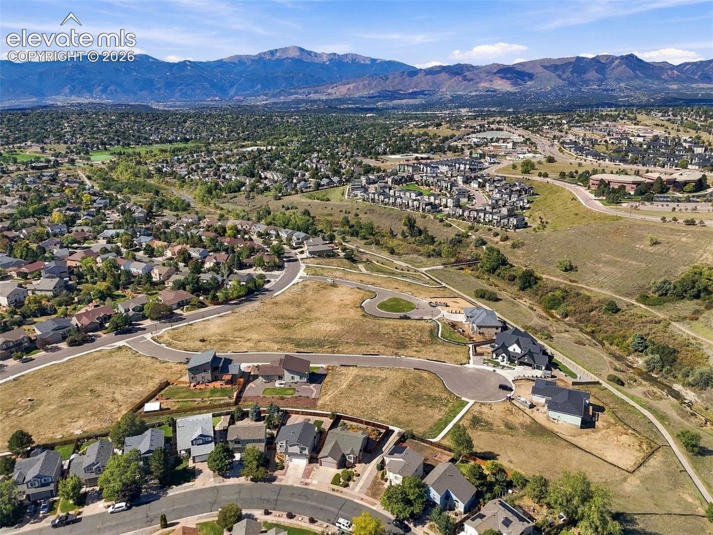 Mountain backdrop, existing neighborhood infrastructure, graded land, residential buildings, and open spaces