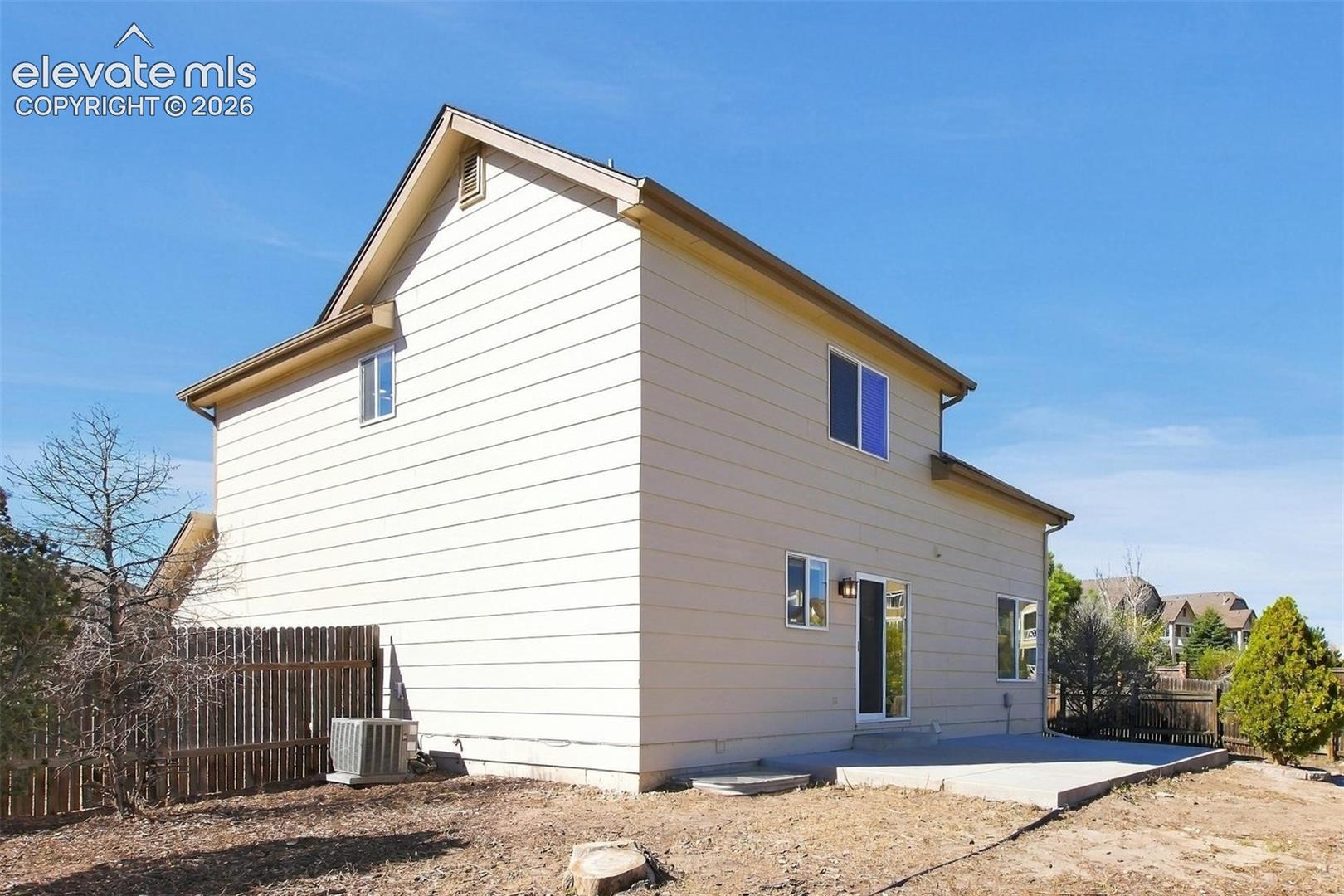 Two-story exterior with horizontal siding, a rear concrete patio, and vertical wood privacy fencing