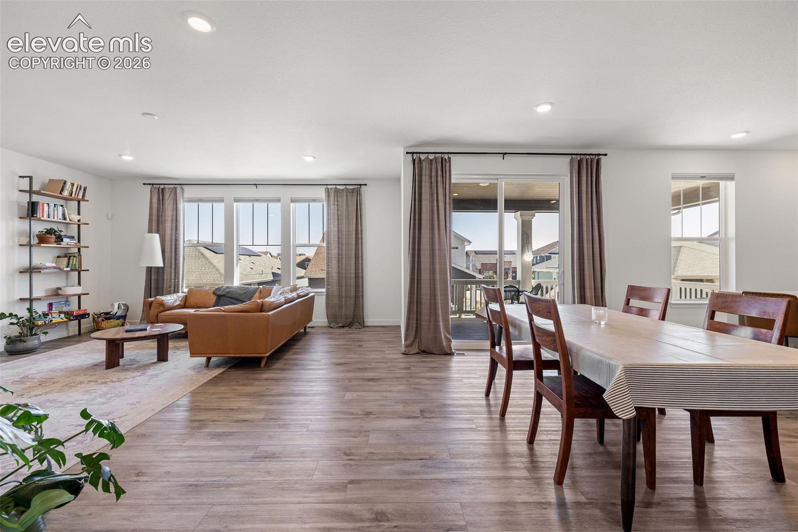 Spacious open-concept living area with LVP flooring, recessed lighting, and multiple windows