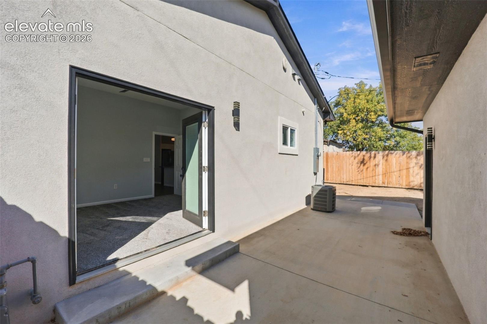 Concrete patio with stucco exterior, dual-pane window, and exterior wall sconces