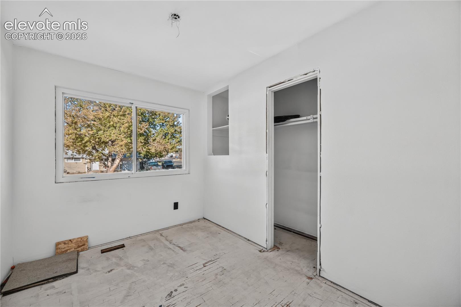Room featuring a sliding window, built-in recessed shelving, and a closet with a fixed hanging rod