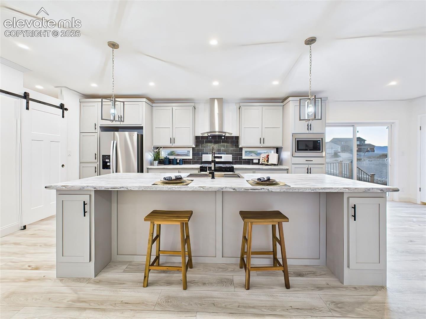 Spacious gourmet kitchen featuring a large center island, stainless steel appliances, and sleek pendant lighting.