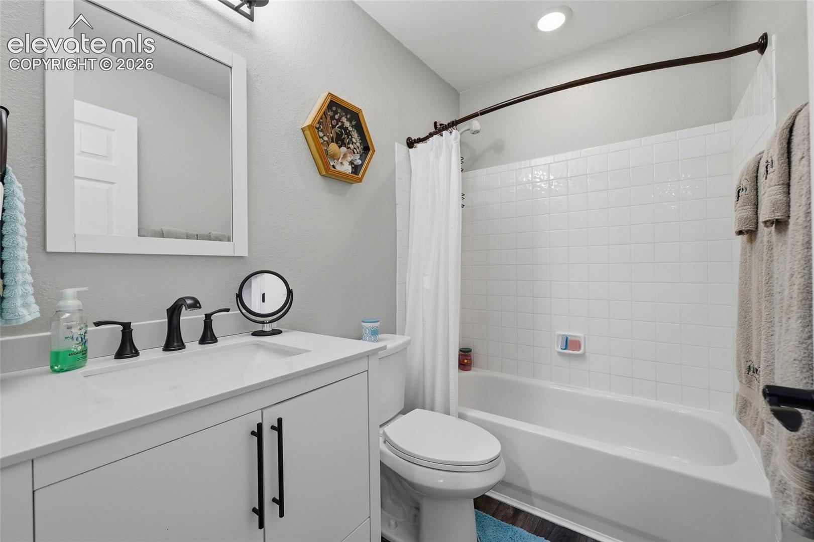 Upstairs classic style hall bath, with white vanity, dual-handle matte black faucet, integrated rectangular sink, and framed mirror