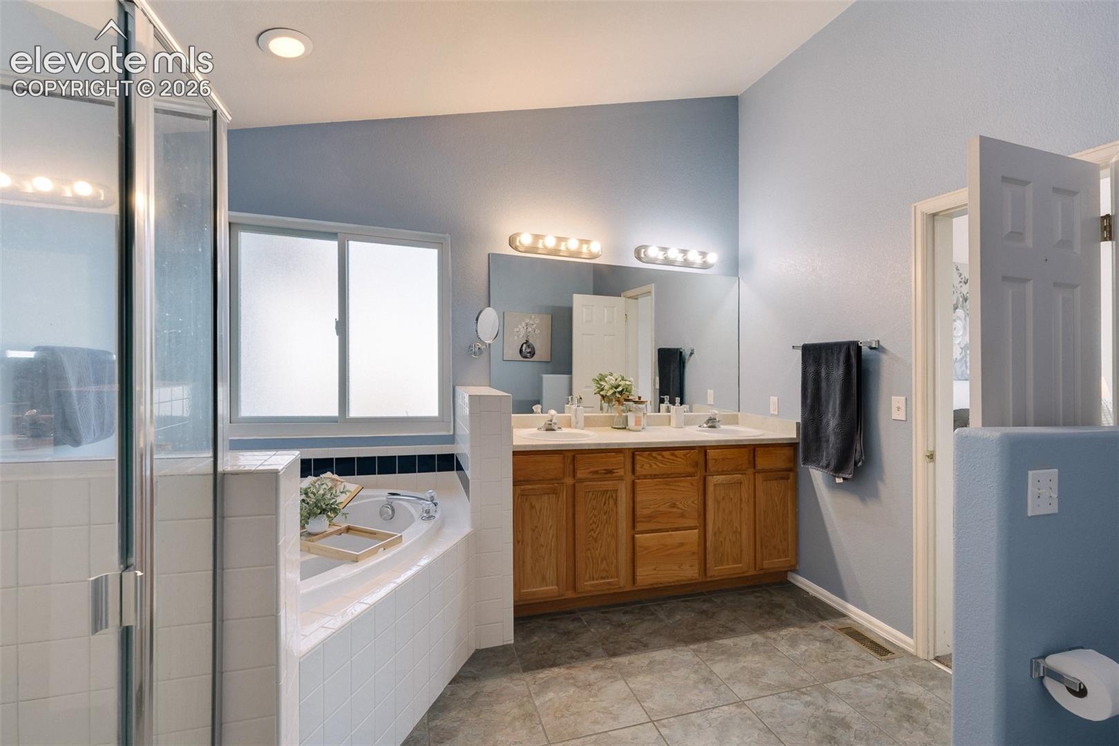 Main level Primary Bathroom with tiled shower, soaking tub, and dual sink vanity.