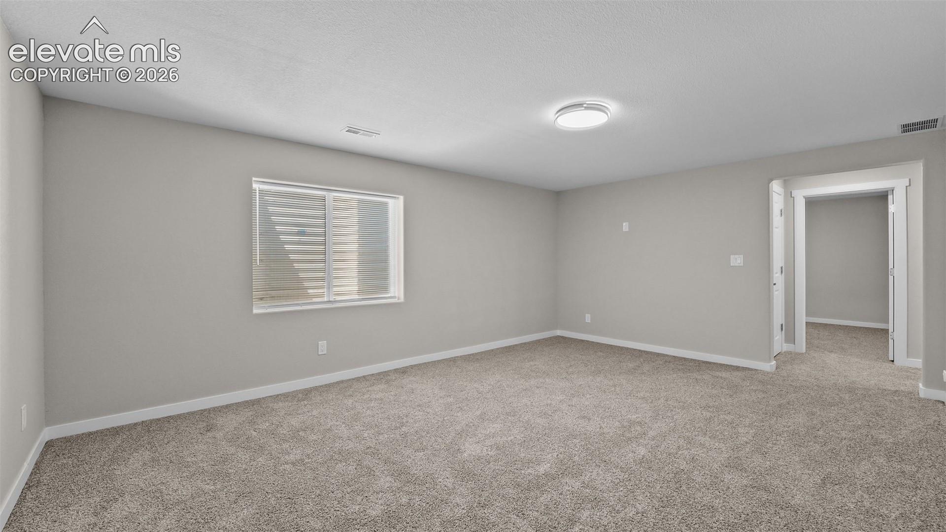 Light-colored carpeting, neutral painted walls, and a window with blinds