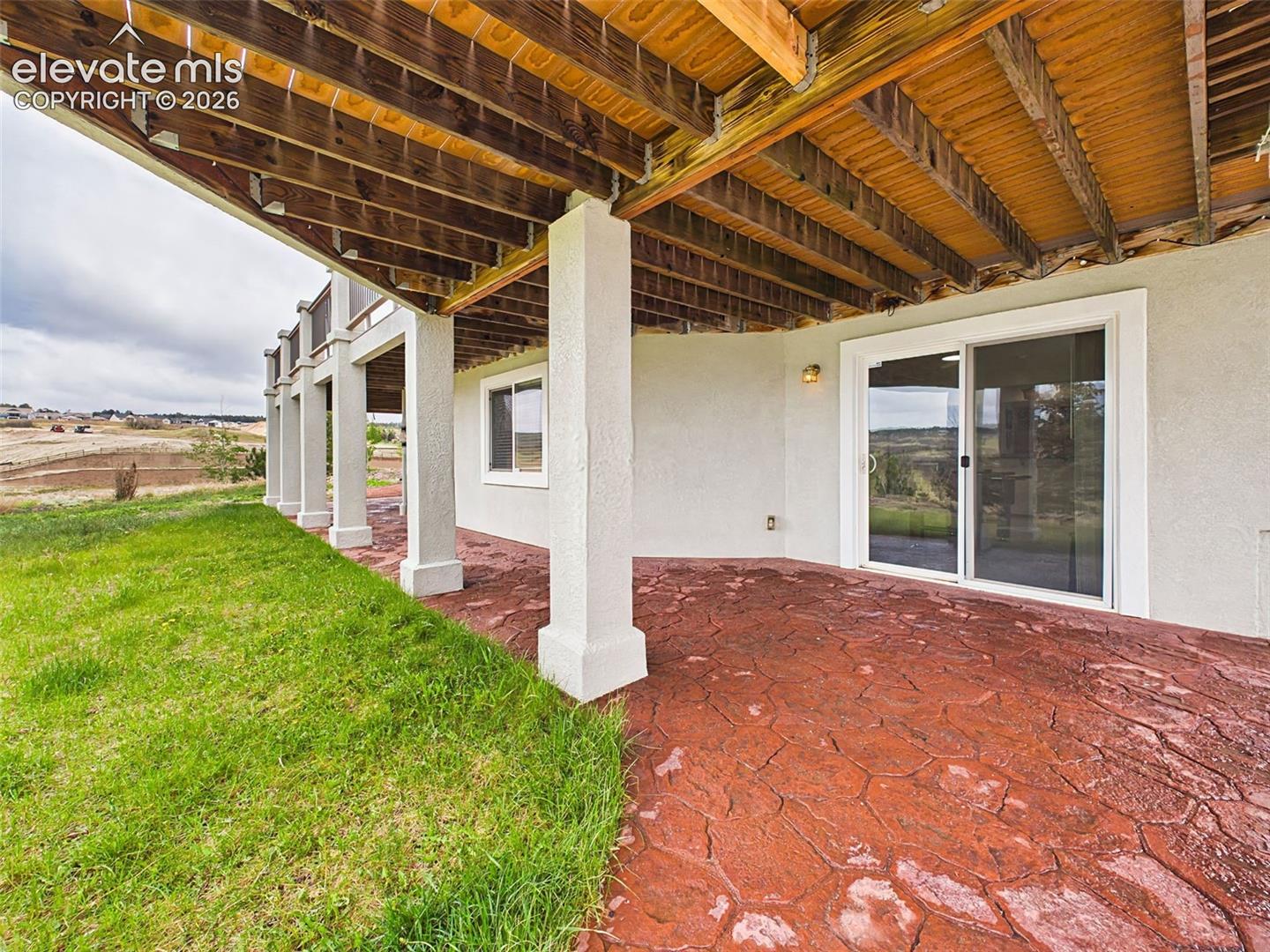 Large covered patio with stamped concrete flooring offers shaded outdoor living and entertaining space year-round.