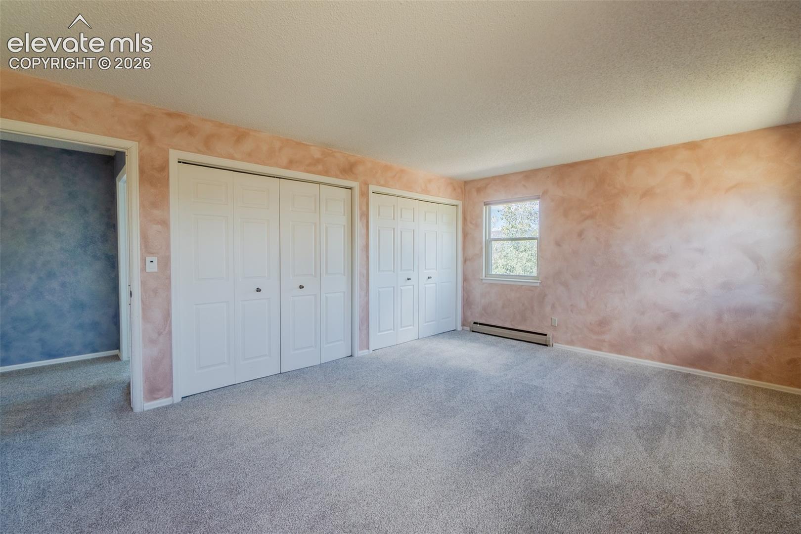 Expansive Fourth bedroom upstairs with new carpet Soft-toned wall finish, multiple bi-fold closet doors, and lots of windows with natural light