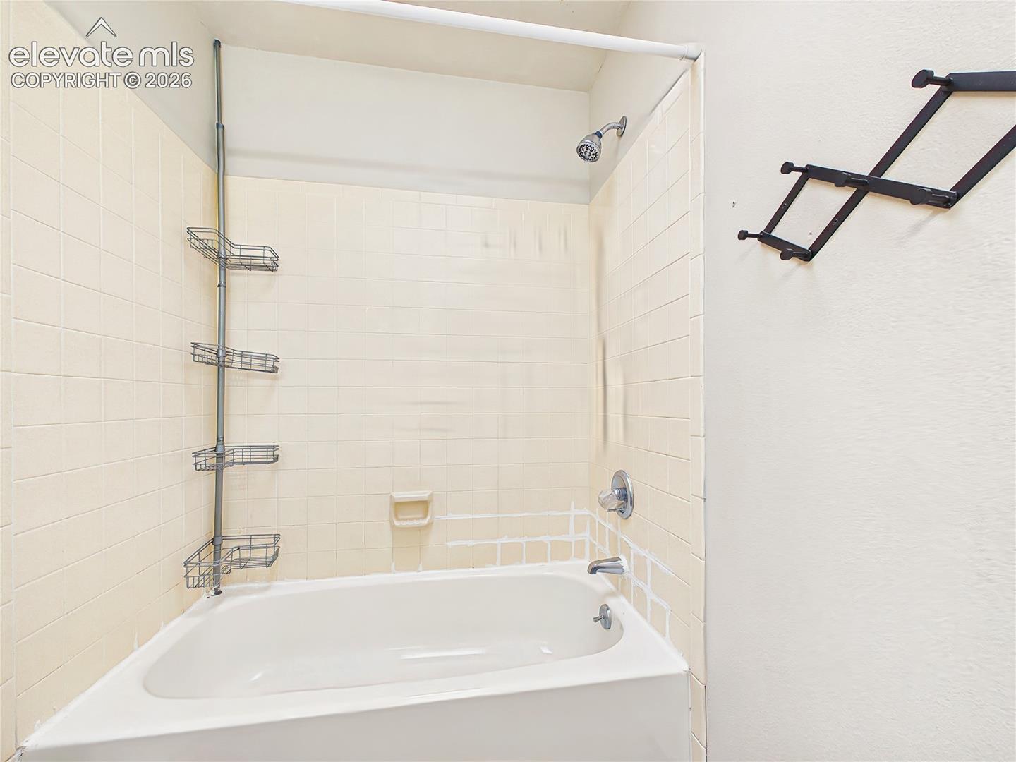 Full bathroom featuring a tub/shower combination with classic tile surround and built-in storage for everyday convenience.