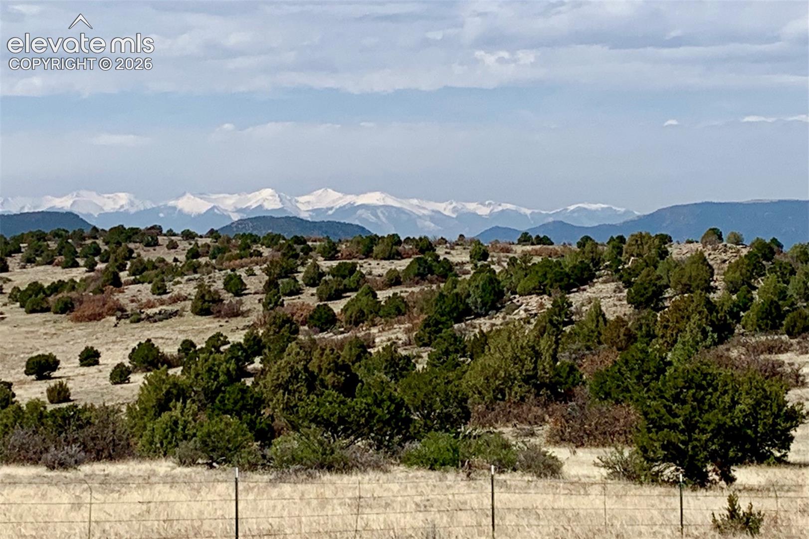 Expansive acreage featuring native juniper trees and a backdrop of snow-capped mountain peaks