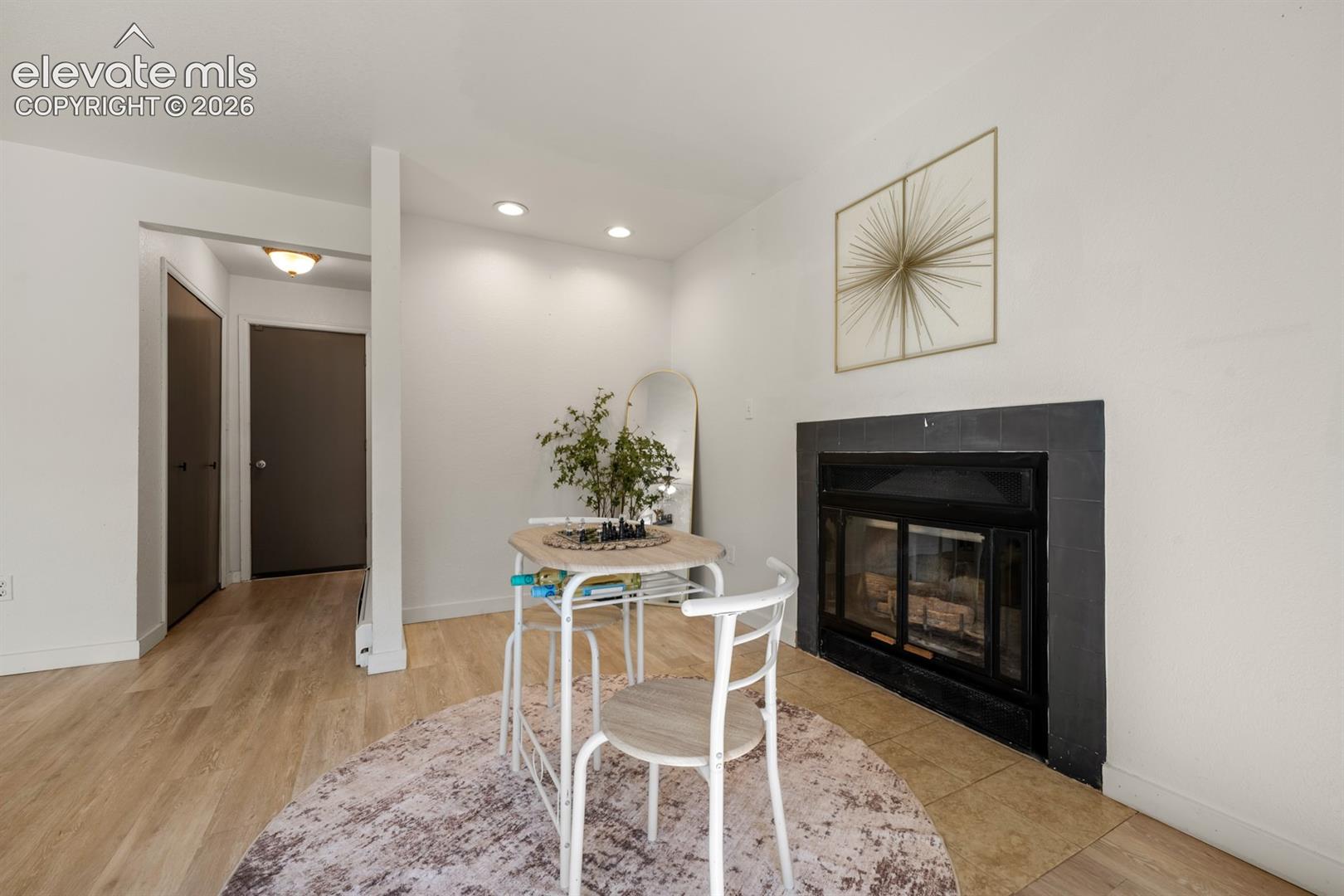 Fireplace with black surround, recessed lighting, and wood-finish flooring