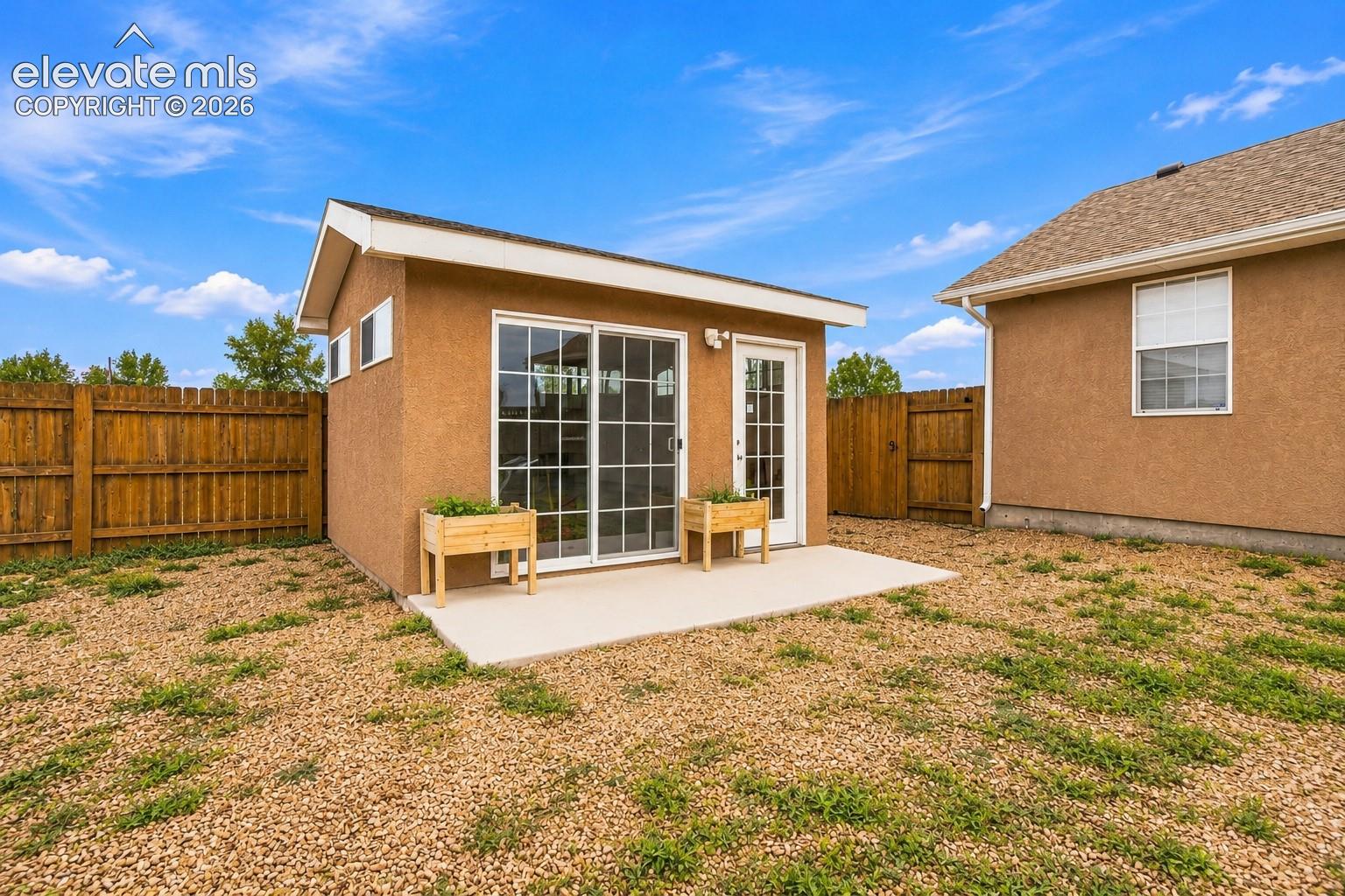Detached structure featuring a textured stucco exterior, sliding glass door, single-entry door, and a concrete patio