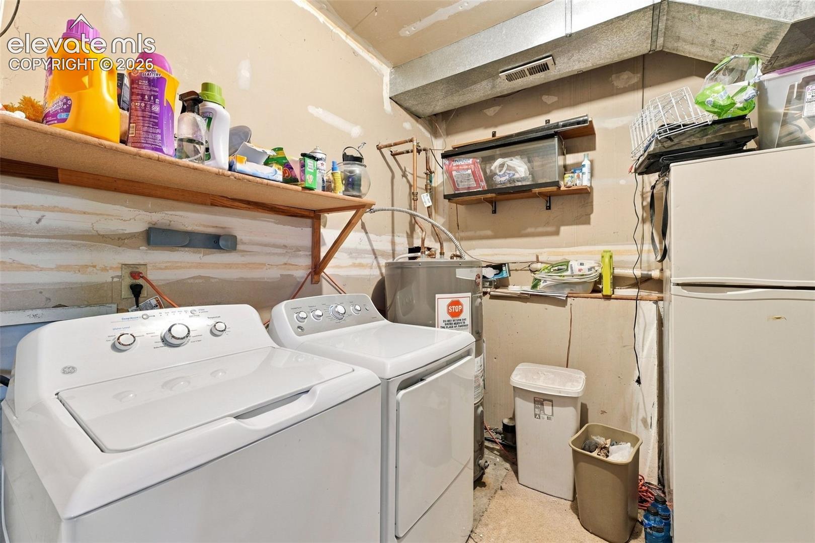 Utility space featuring a water heater, exposed piping, wall-mounted wood shelving, and metal ductwork